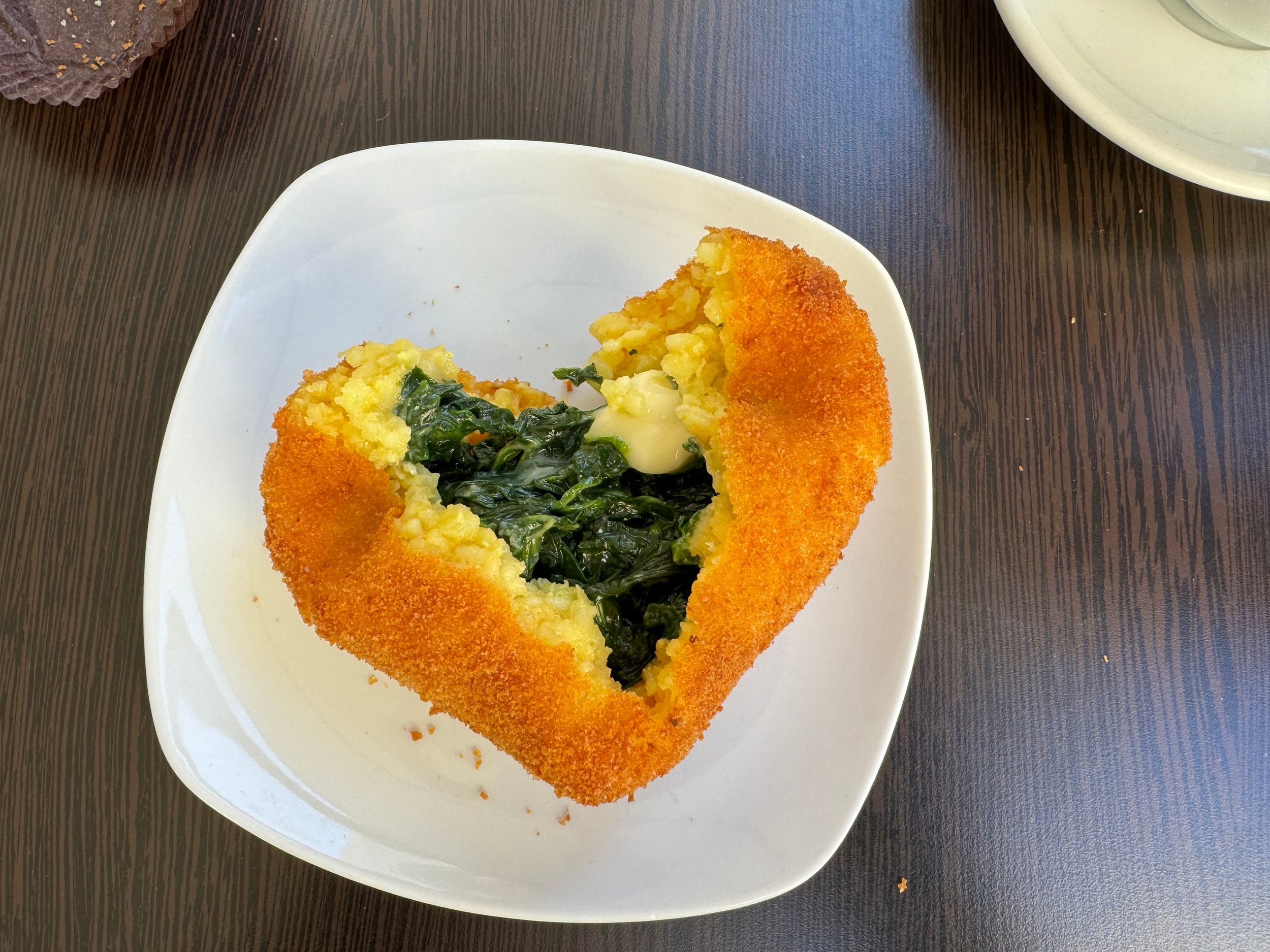  Arancini, a staple of Sicilian cuisine, are rice balls that are stuffed, coated with breadcrumbs and deep-fried. Typically stuffed with meat, this is spinach arancini.  