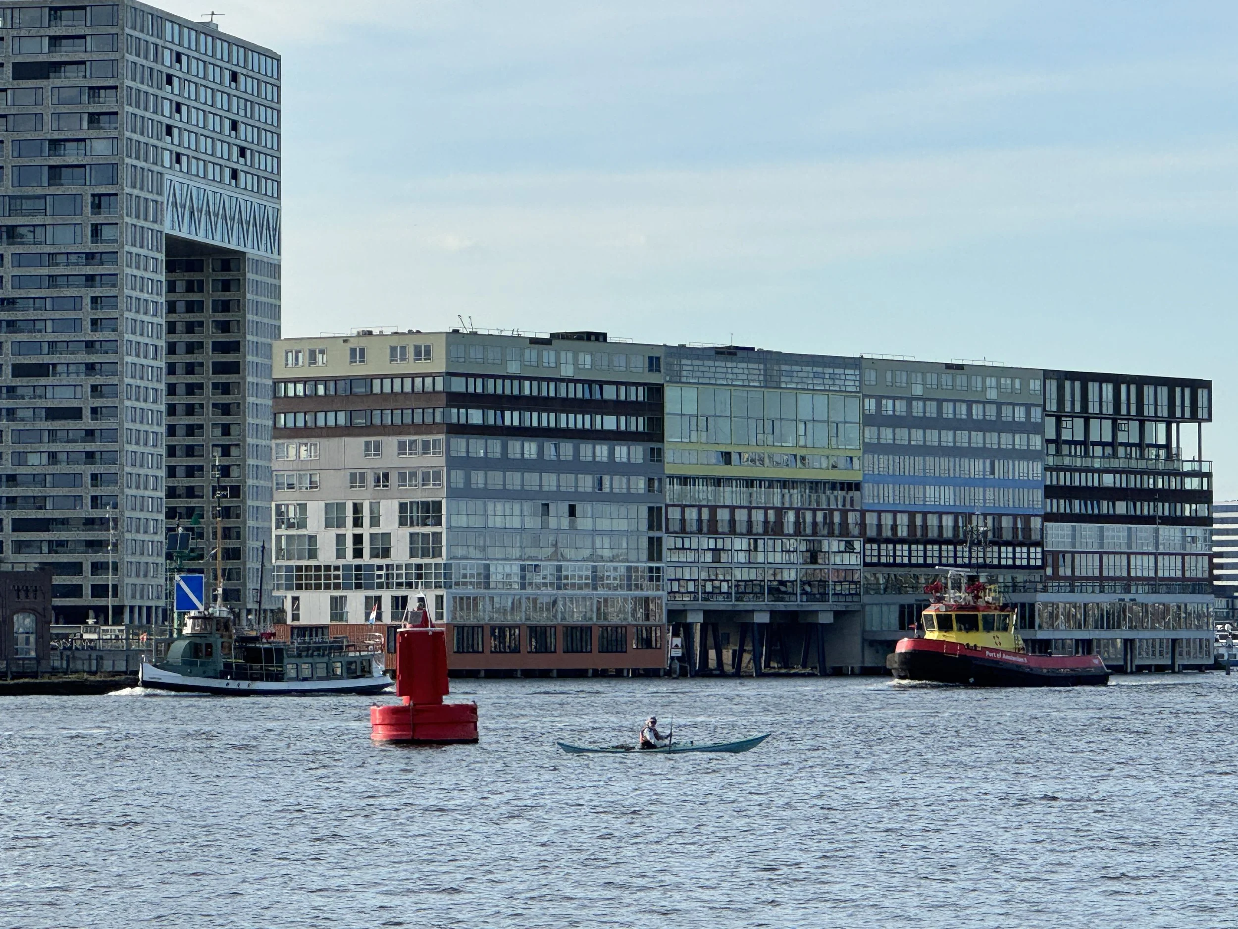   A kayaker dodges ferries, tugs, cruise ships, barges and pleasure craft in central Amsterdam.  