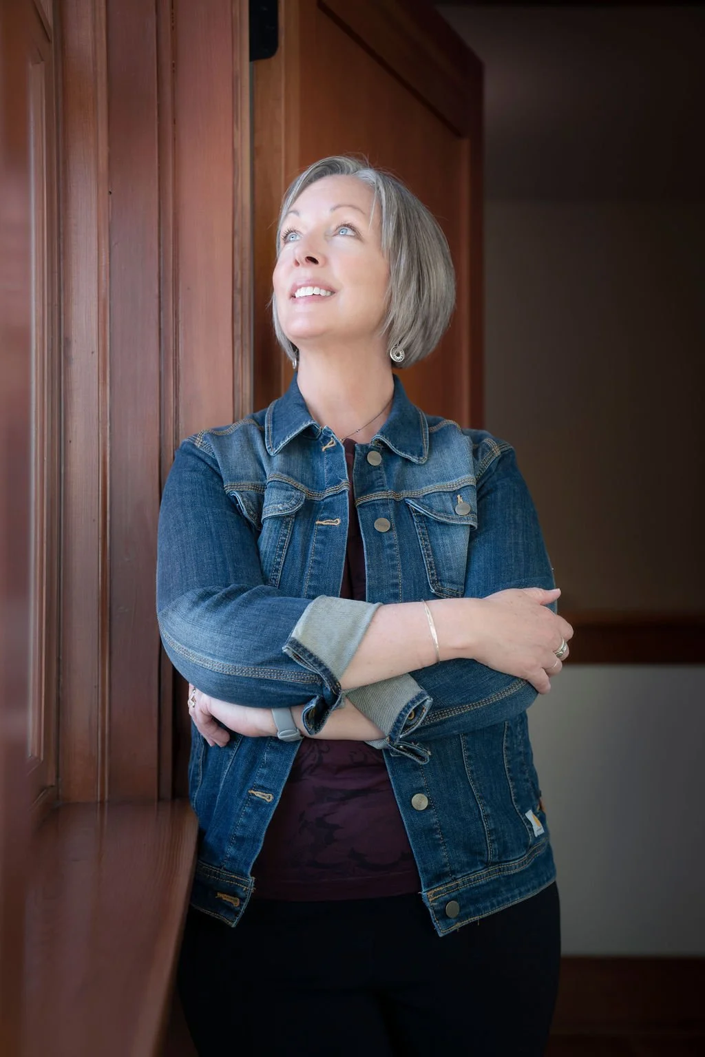 Image of Diane Green, web designer for small businesses and entrepreneurs, is wearing a blue denim jacket and looking up with a smile.
