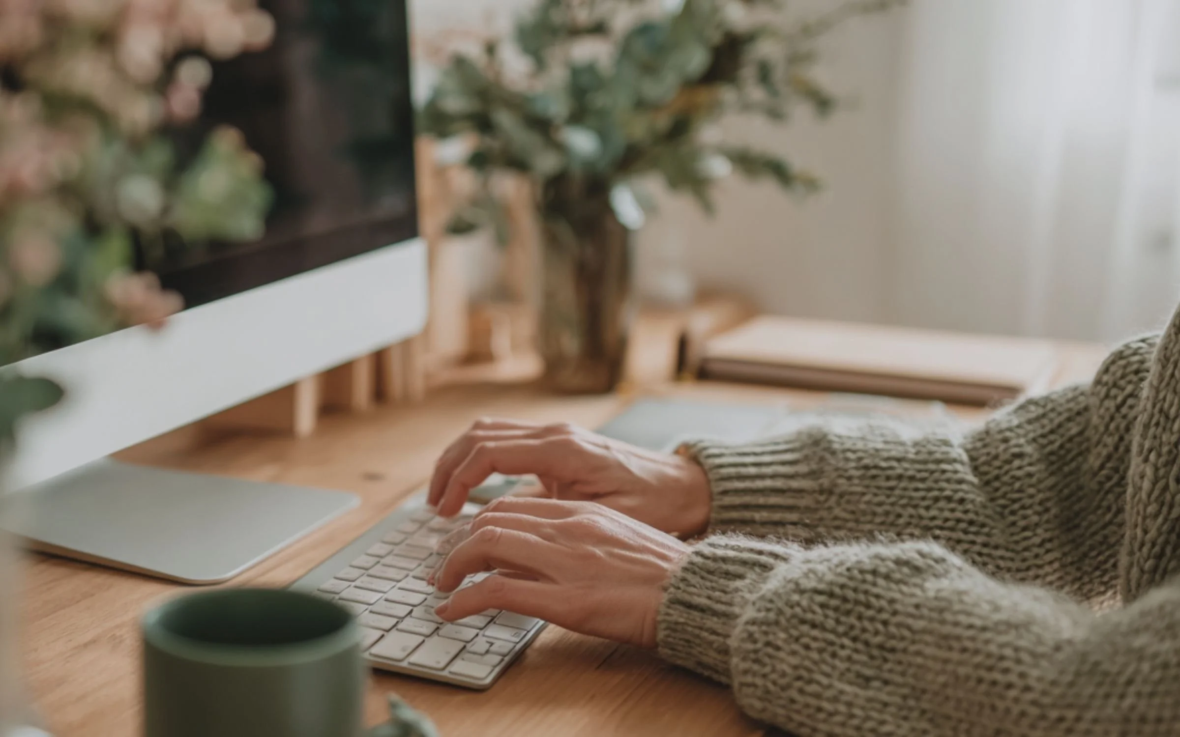 web designer on a keyboard in front of a computer monitor with a blurred background.