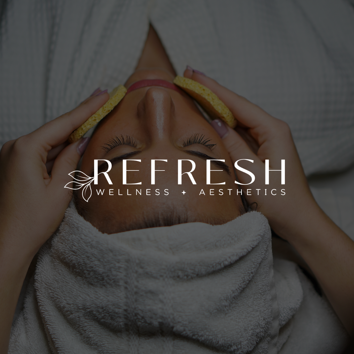 A woman receiving a facial massage in a spa, with a towel wrapped around her hair and yellow sponges on her face, promoting wellness and aesthetics.