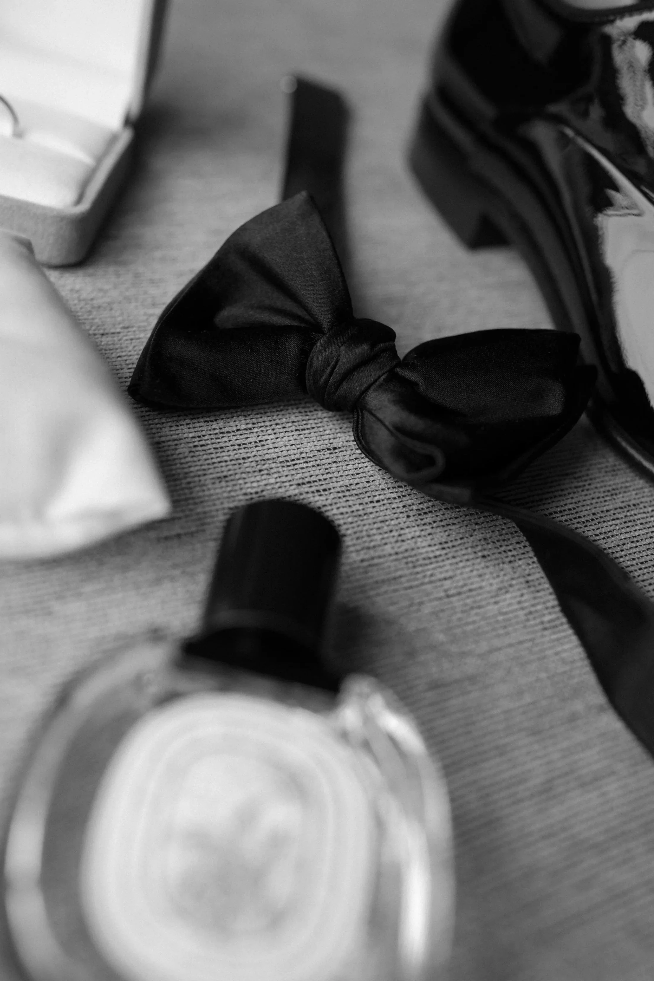 Black bow tie and other accessories on a textured surface.
