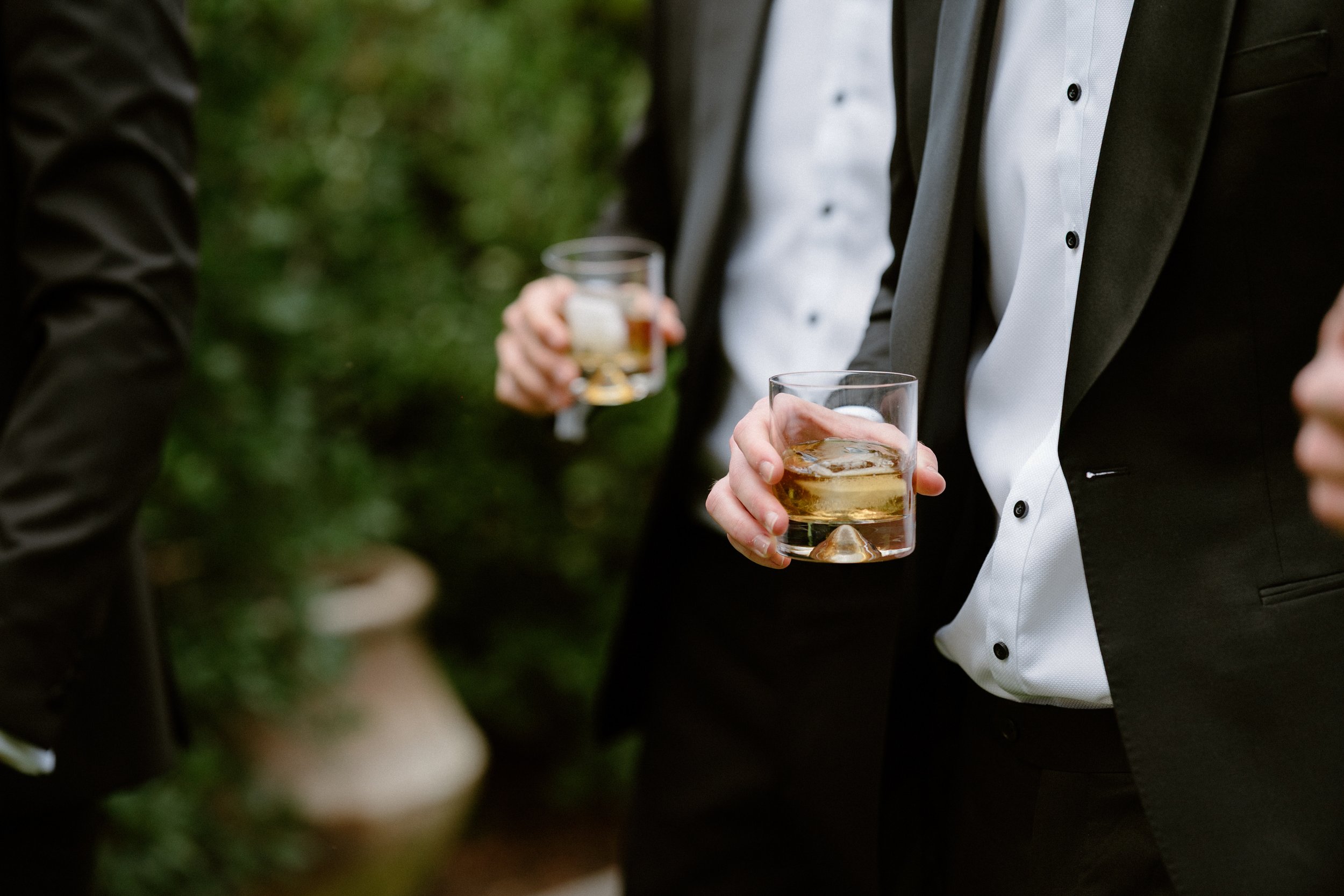 People in formal attire holding glasses of whiskey or similar drink during a social gathering.