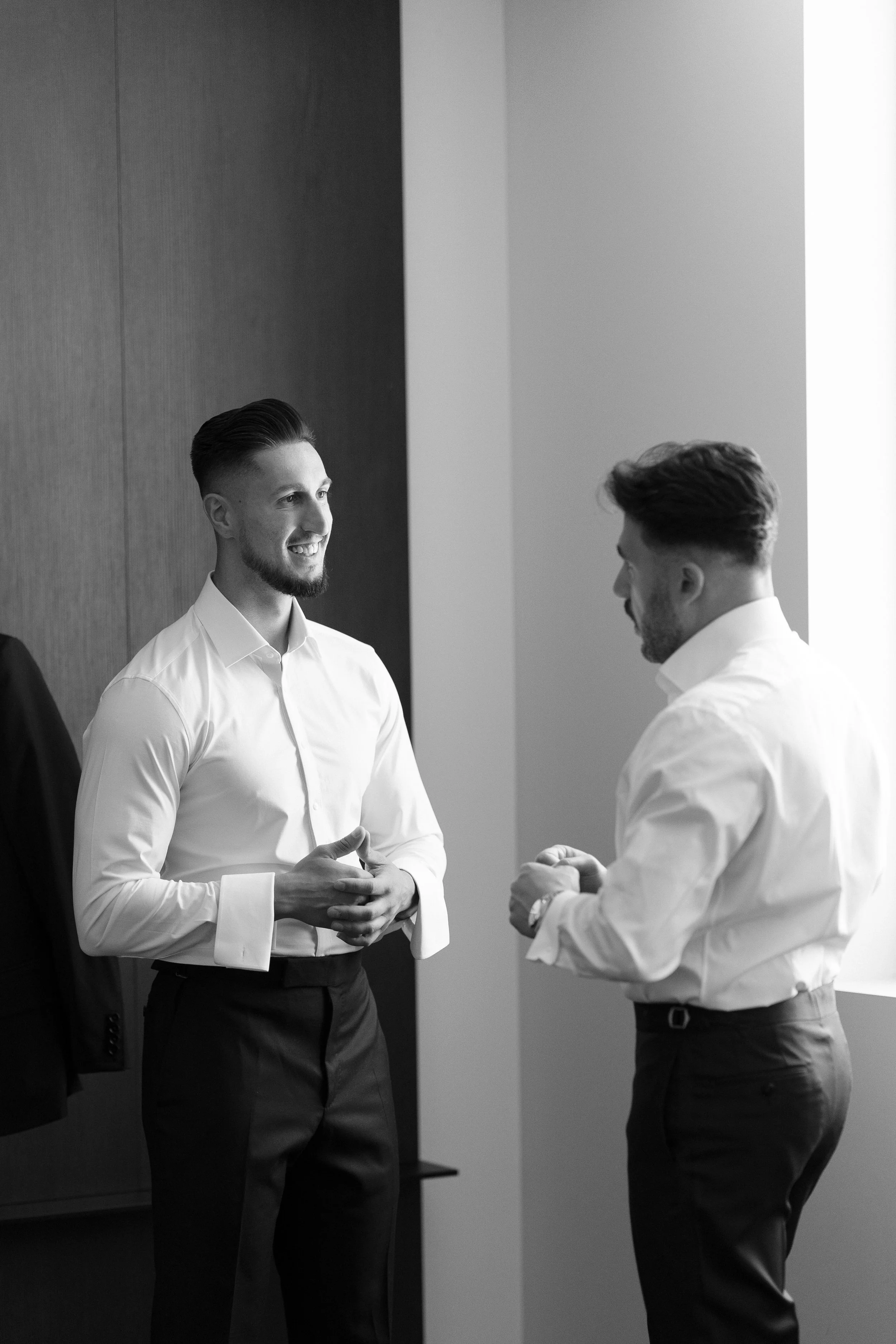 Two men in dress shirts having a conversation indoors.