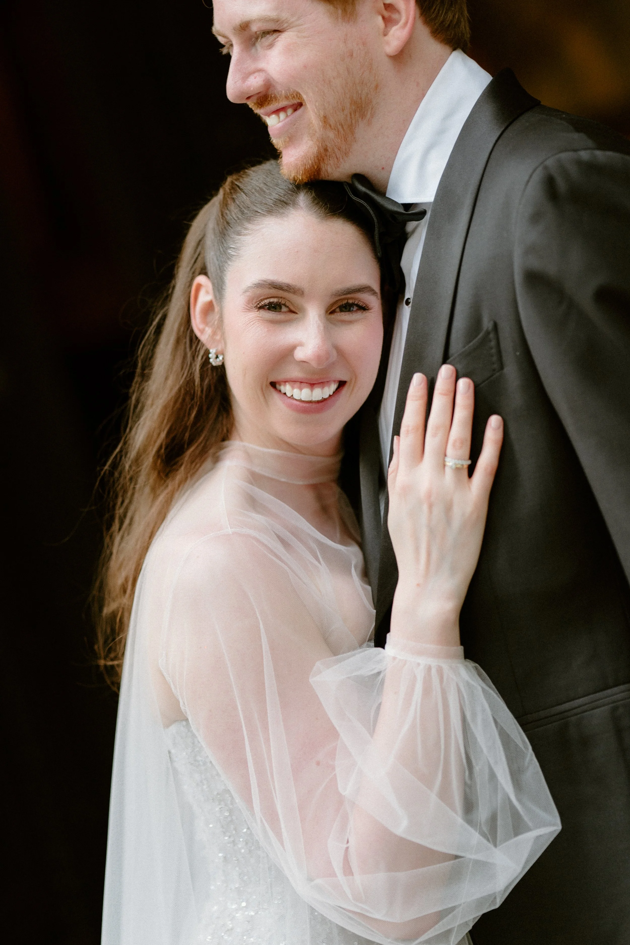 A happy bride and groom dancing at their wedding, with the bride smiling and embracing the groom, who is wearing a tuxedo.