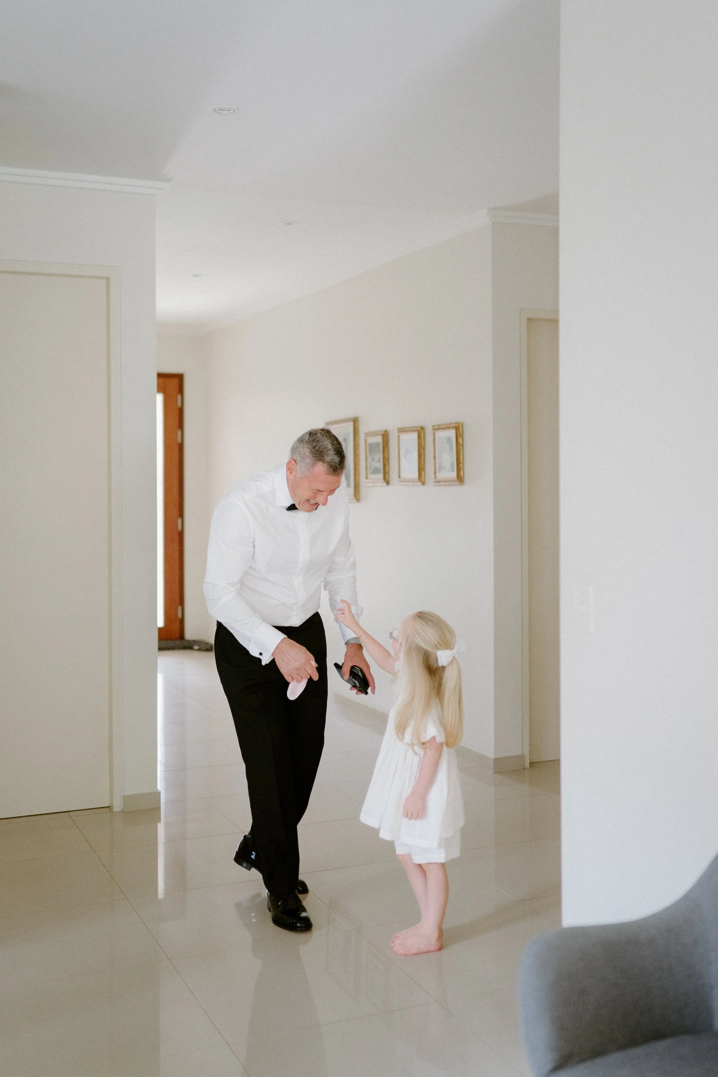 A man and a young girl sharing a joyful moment in a brightly lit home interior.