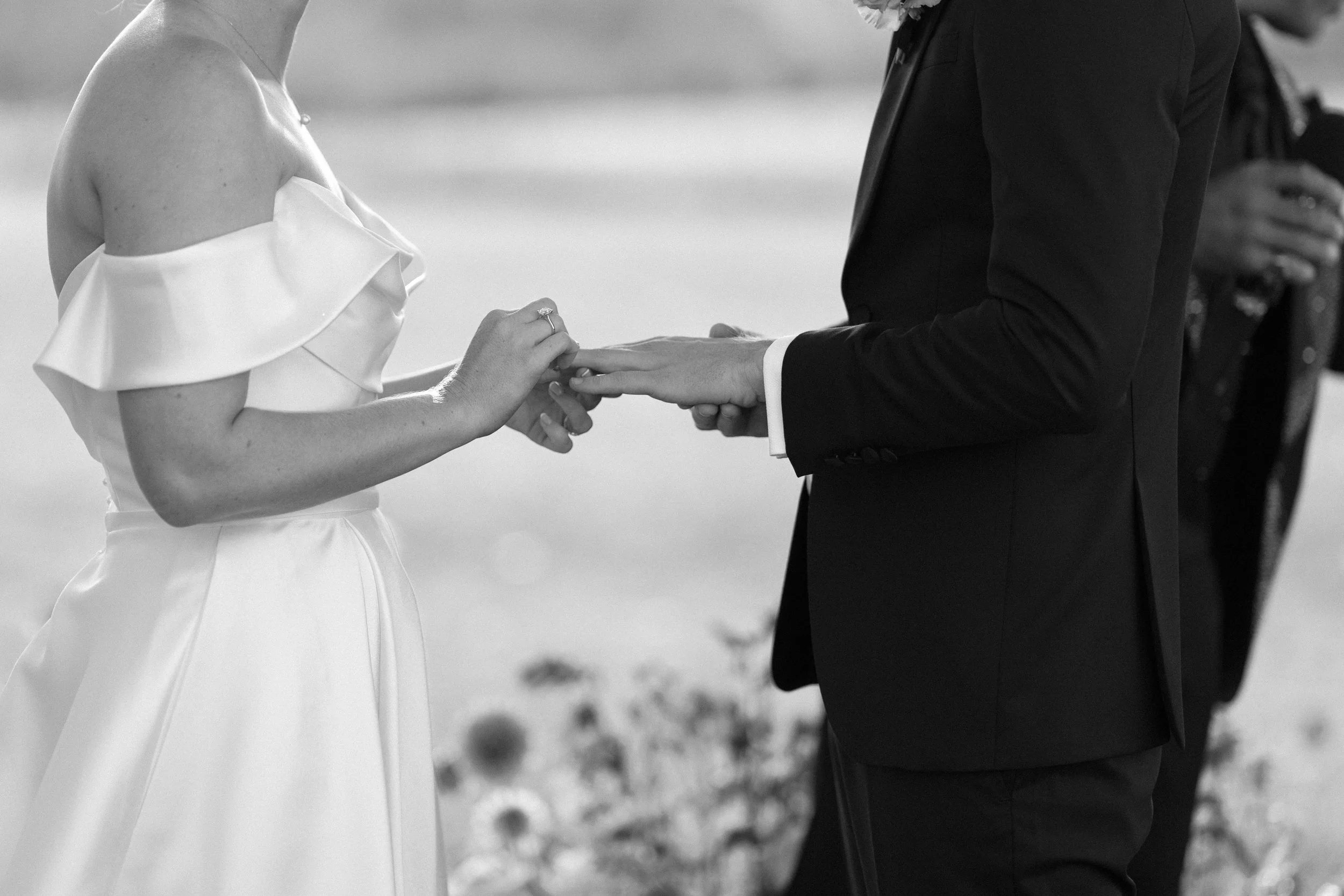 Couple exchanging rings during wedding ceremony outdoors