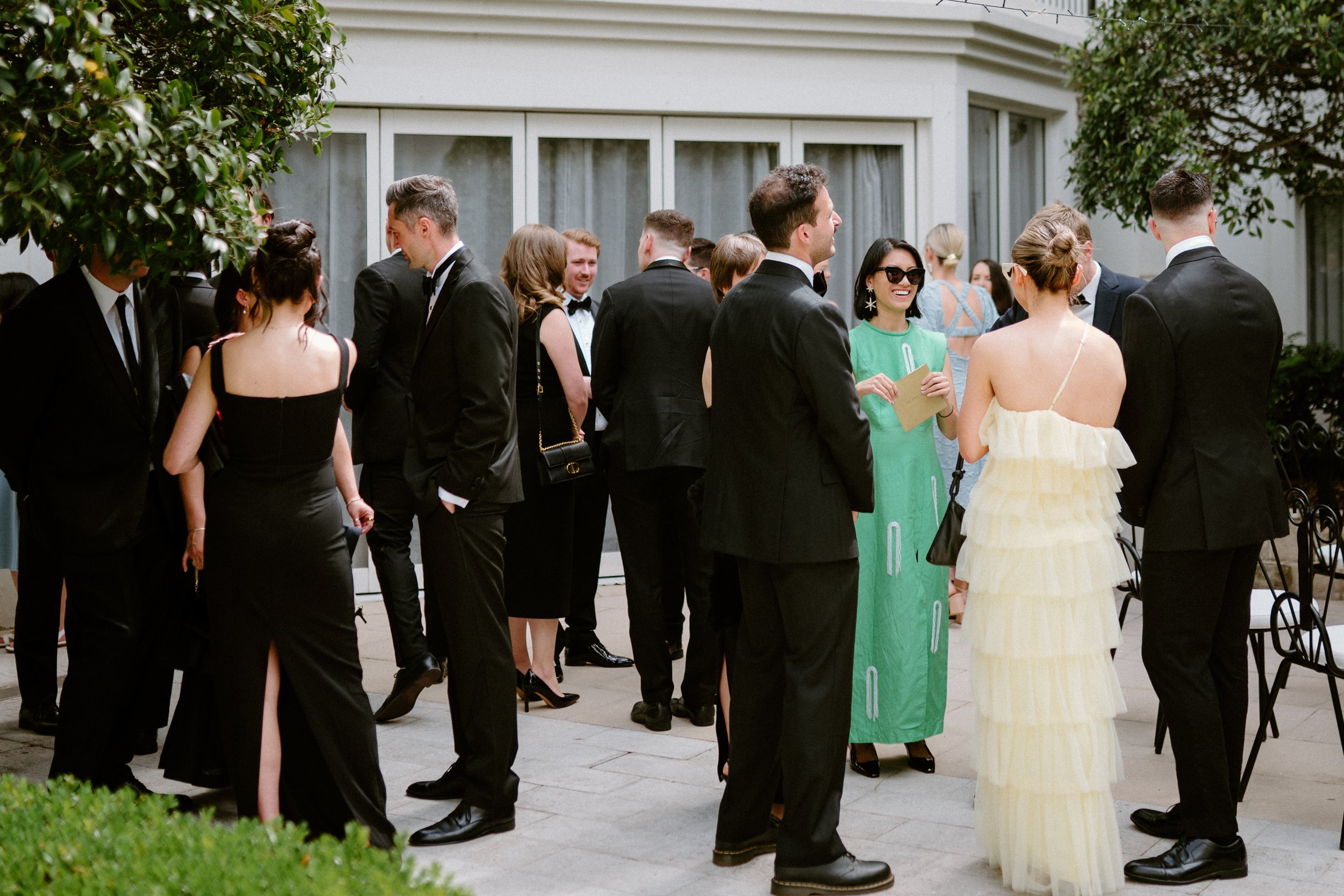 Group of people dressed in formal attire socializing outdoors at an event.