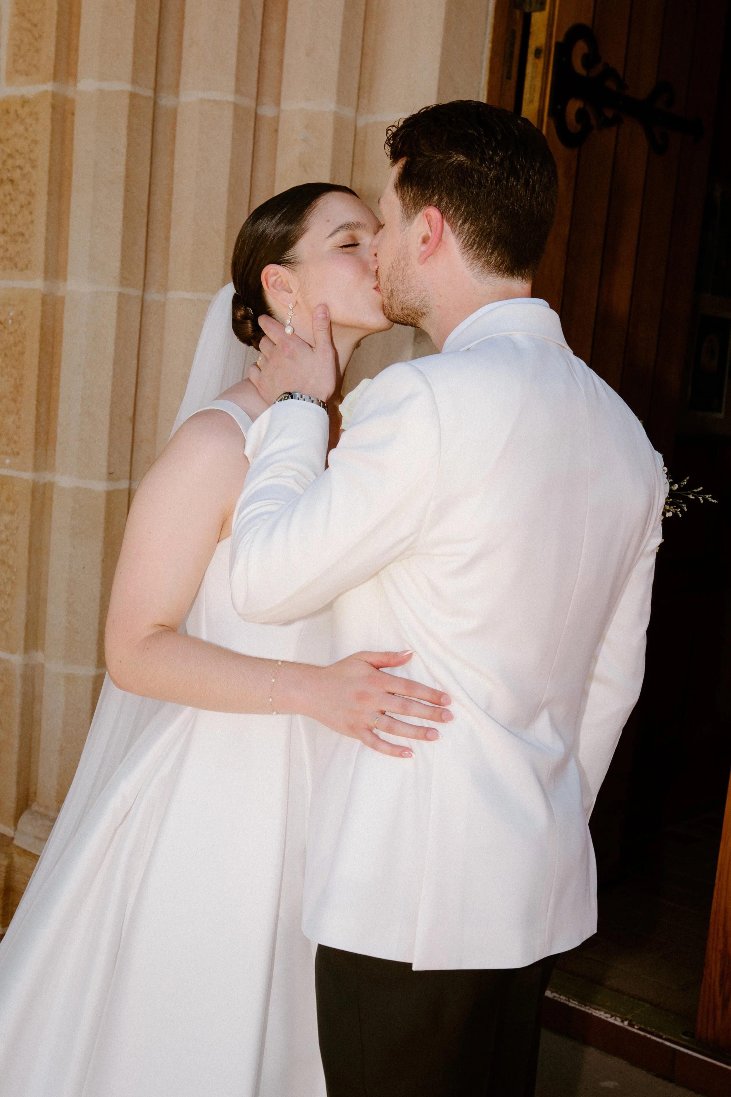 A bride and groom kissing during their wedding ceremony indoors.