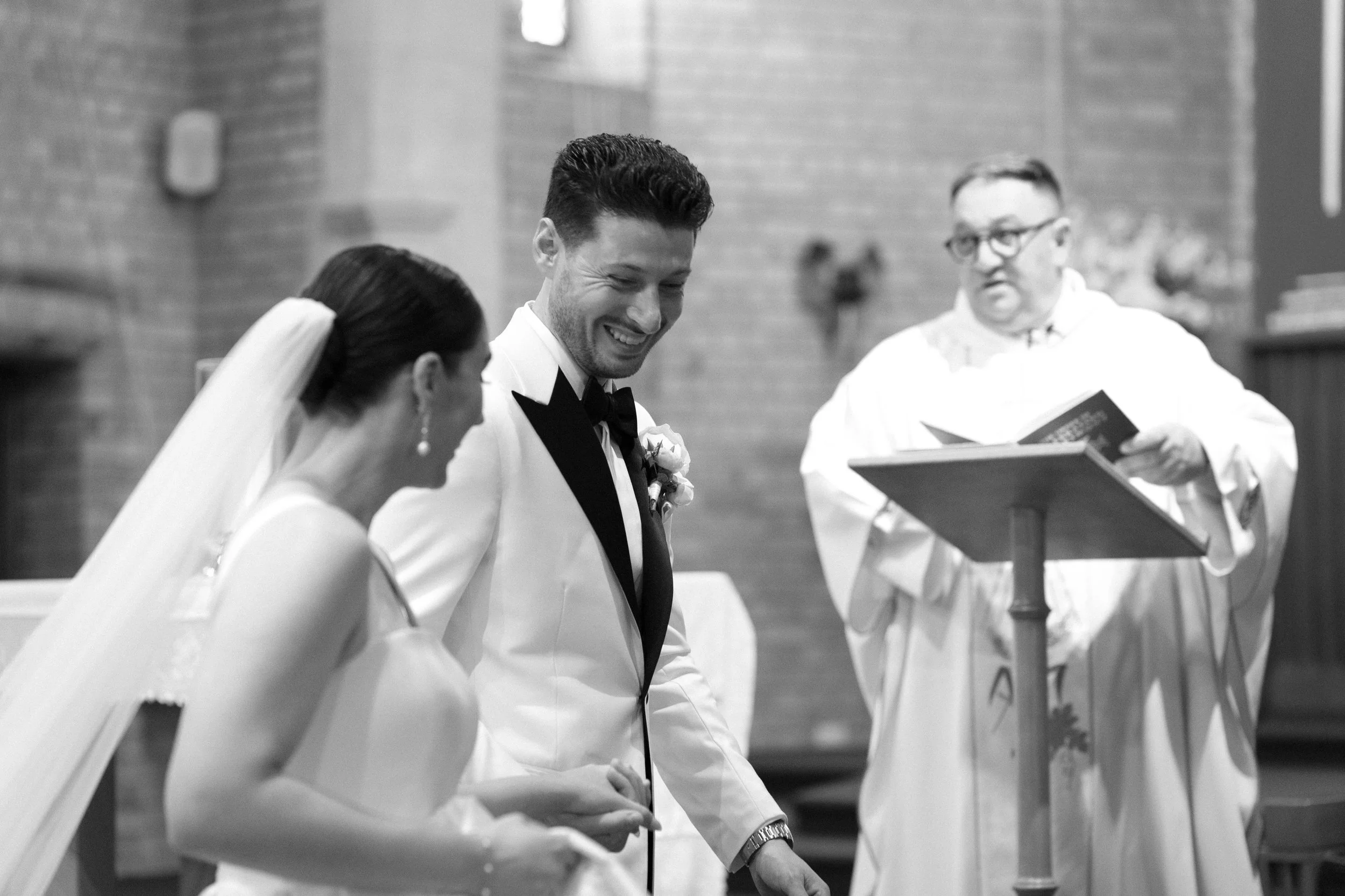 A bride and groom exchanging vows during a wedding ceremony in a church, with a priest officiating.