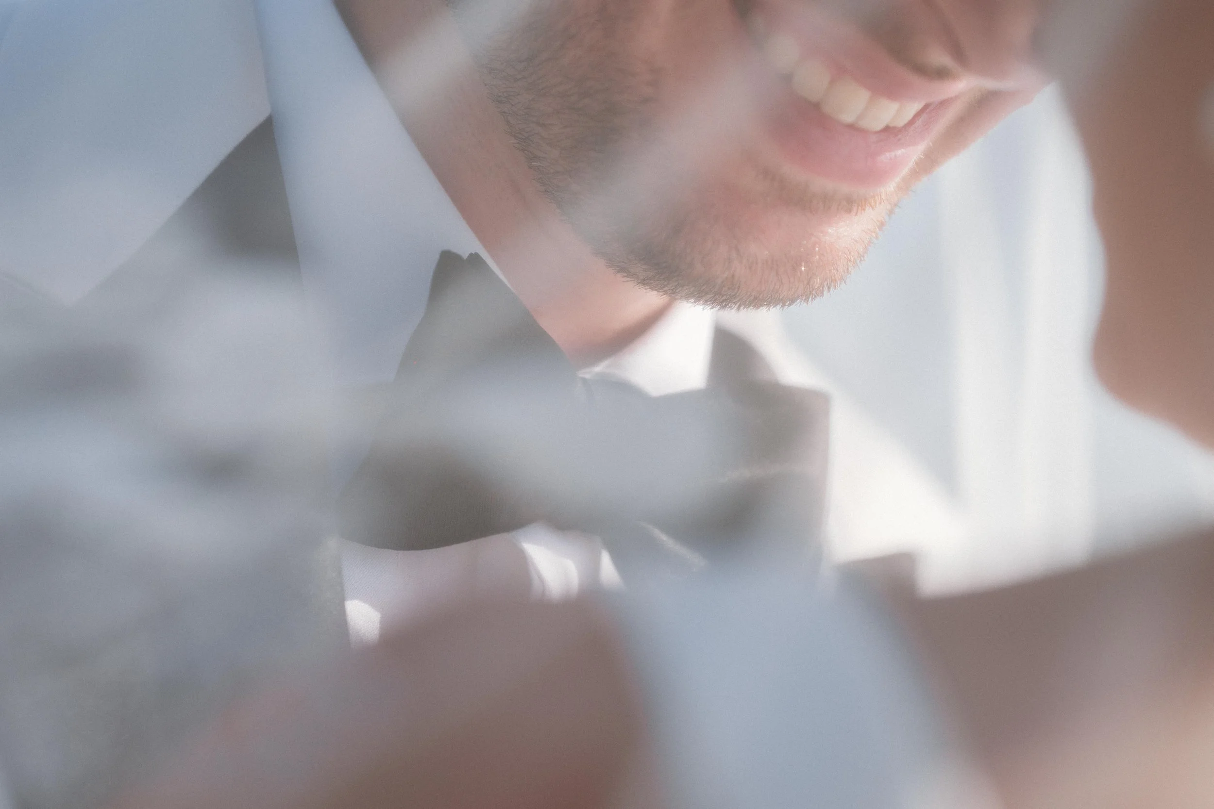 Close-up of a smiling man wearing a tuxedo with a bow tie, showing part of his face and beard.