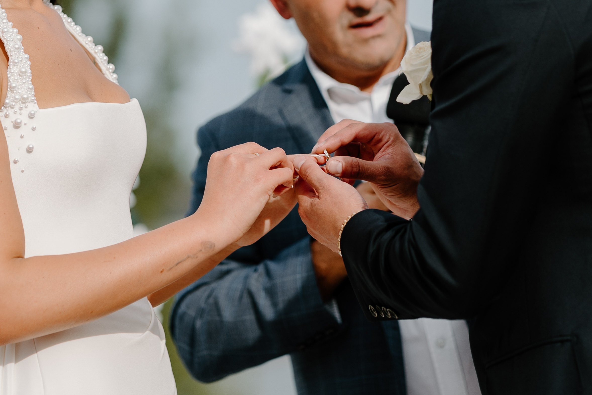 Person getting a wedding ring placed on their finger during a wedding ceremony.