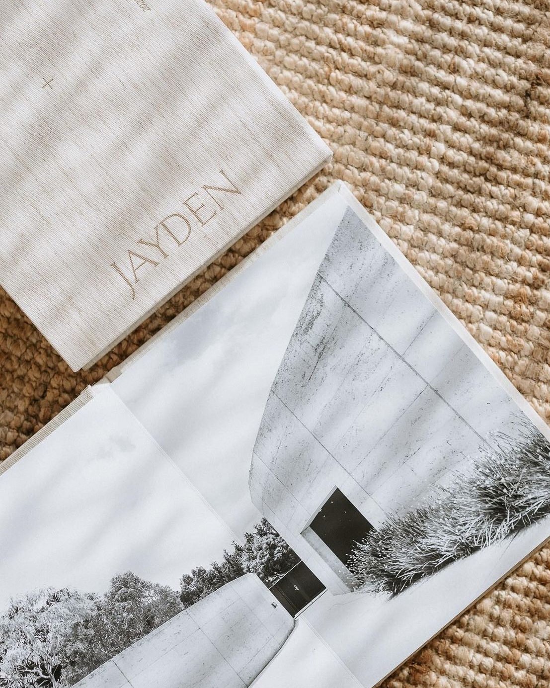 Open JAYDEN photography brochure with a black and white photo of a modern concrete building, resting on a textured beige rug.