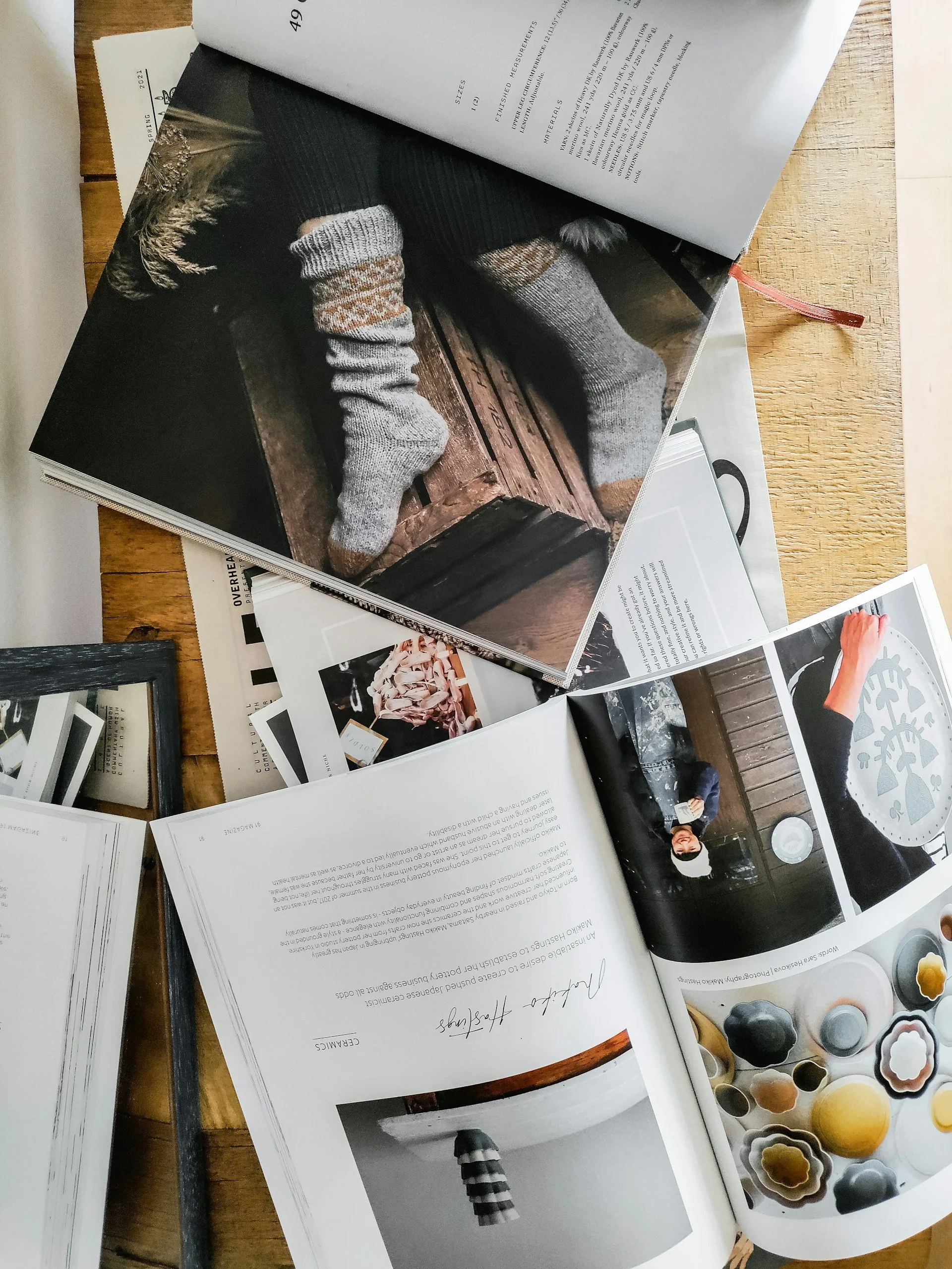 Magazines ouverts sur une table en bois avec des chaussettes en laine grise tricotée — ambiance cocooning hivernal