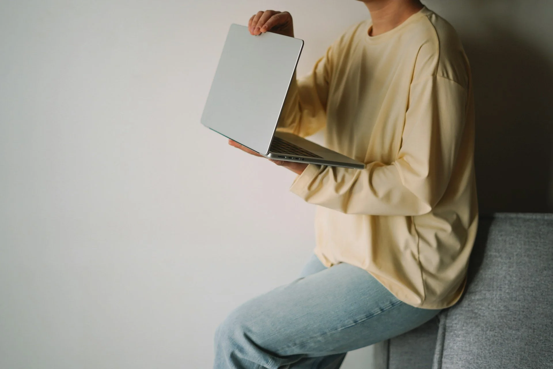 Femme assise, son ordinateur portable entre les mains — un moment pour regarder où elle en est.