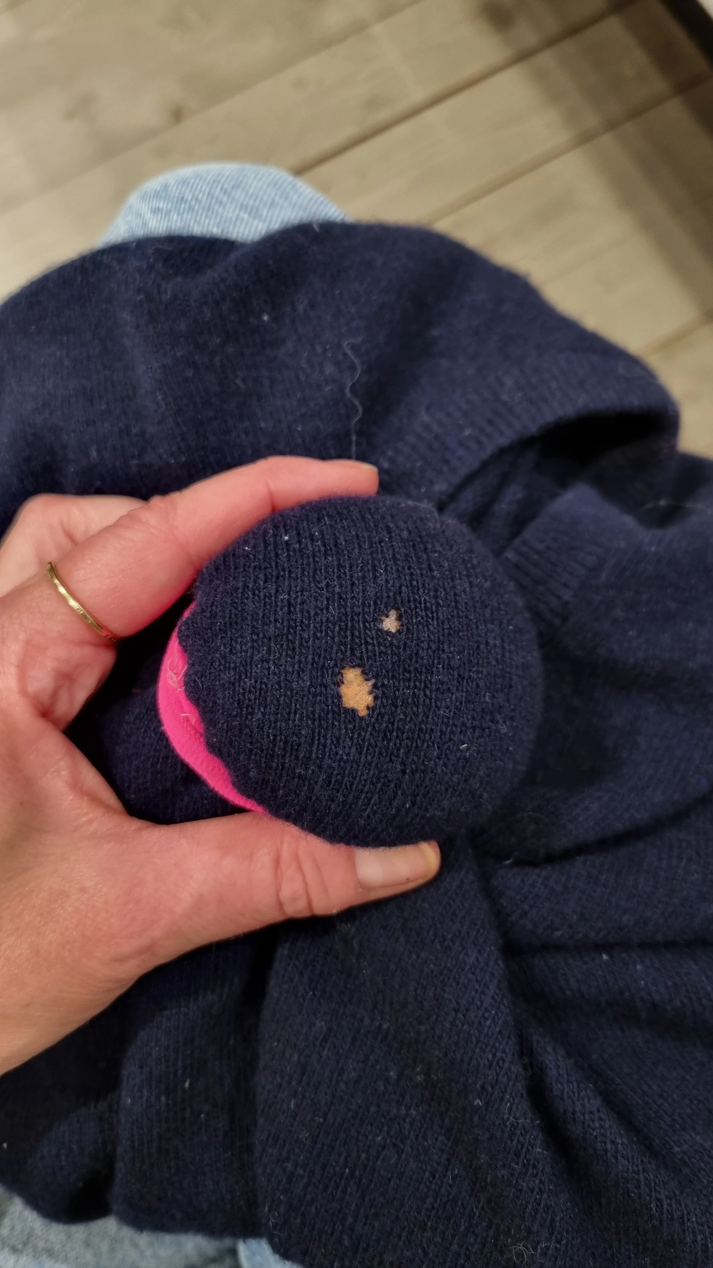 Hand hält löchrigen blauen Pull über einem Stopfpilz gespannt.