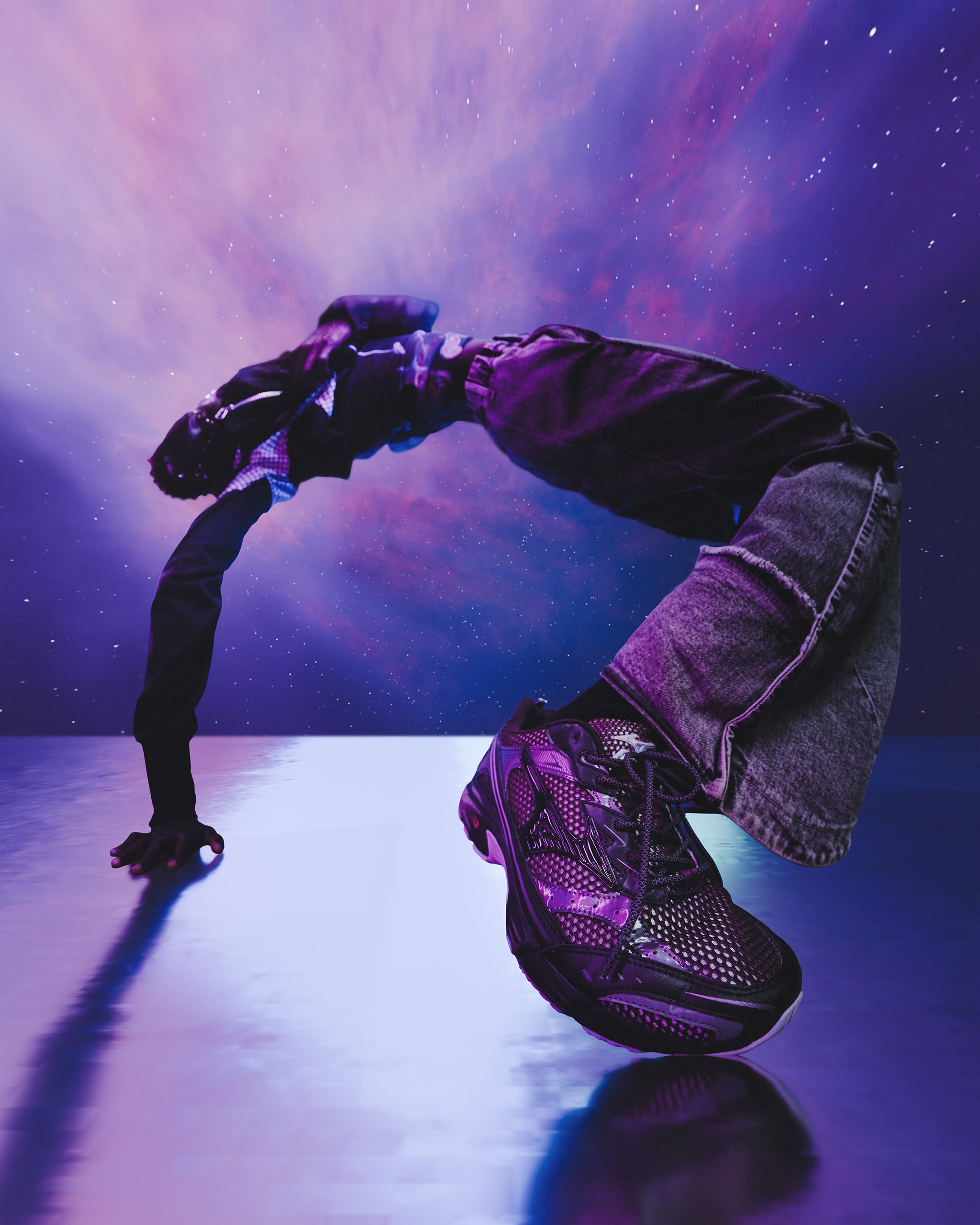 Person in athletic gear performing a backbend on a shiny reflective surface with a starry sky and colorful nebula in the background.