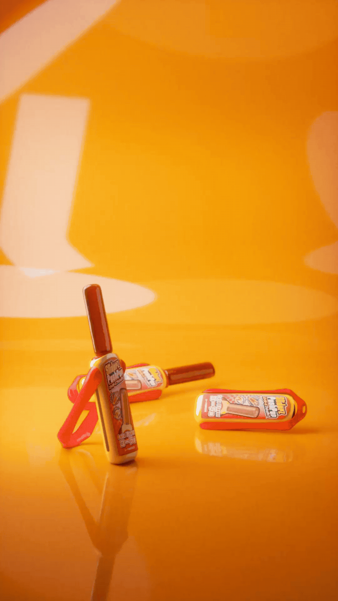 Three small toy bottles with brown caps are placed on a shiny orange surface. Two bottles are lying down, while one is standing upright with a pink clip attached.