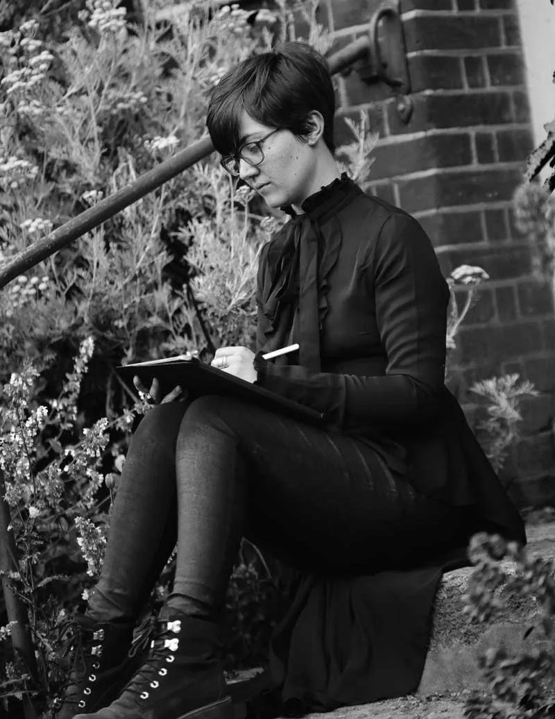 Black and White image of Hollie Quinn sketching on location in Flatford Mill, Suffolk