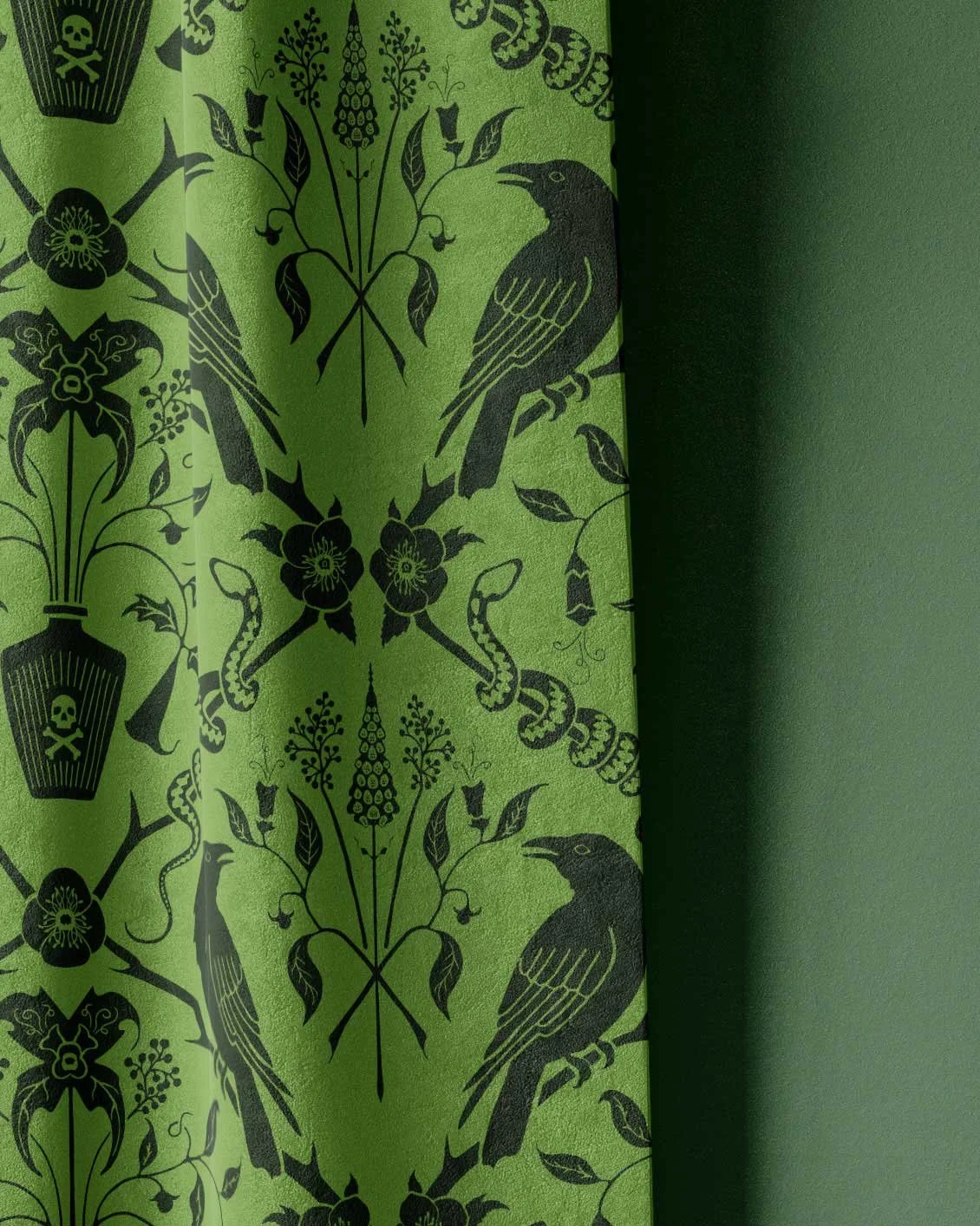 Green fabric with black decorative pattern featuring crows, snakes, flowers, and poison skulls in a symmetrical design.
