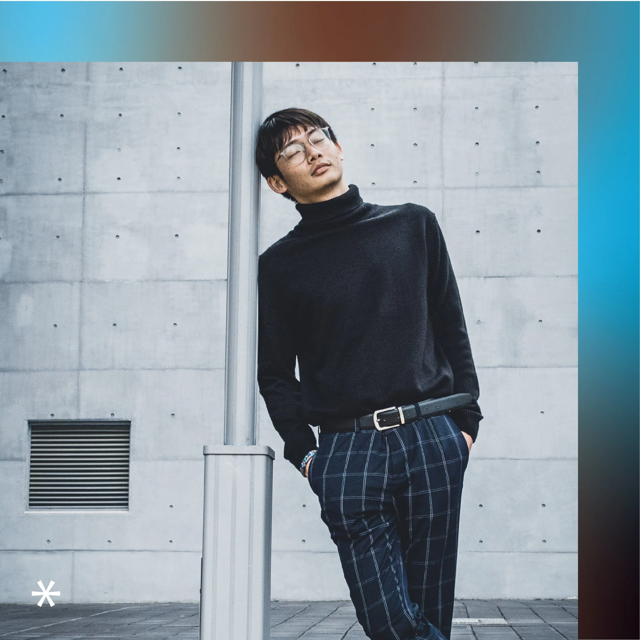 Trendy man leaning against a light pole.