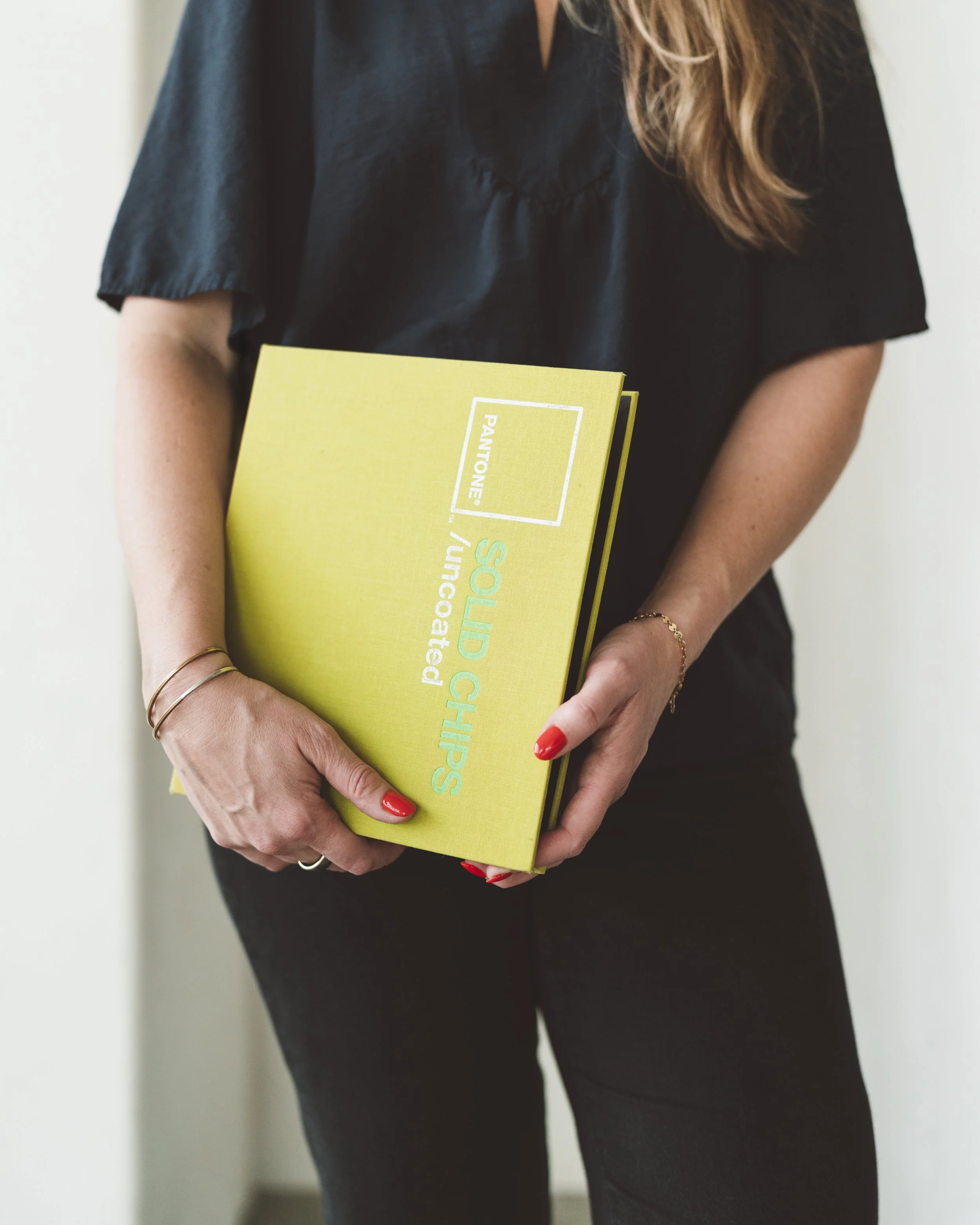 Person holding a yellow book titled 'Solid Chips' with a green background, wearing a black top and with red painted nails.