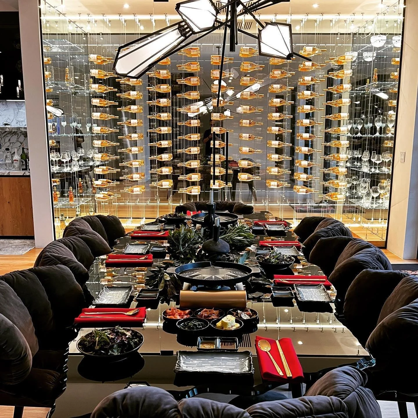 Private Korean BBQ dinner table set in front of a glass wine wall