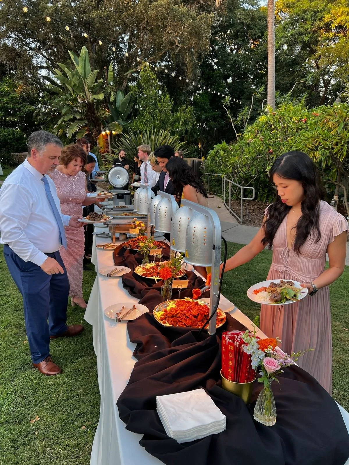 Wedding guests serving themselves at an outdoor Korean catering buffet