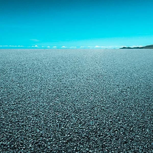 A vast salt flat with a clear blue sky and distant hills on the horizon.
