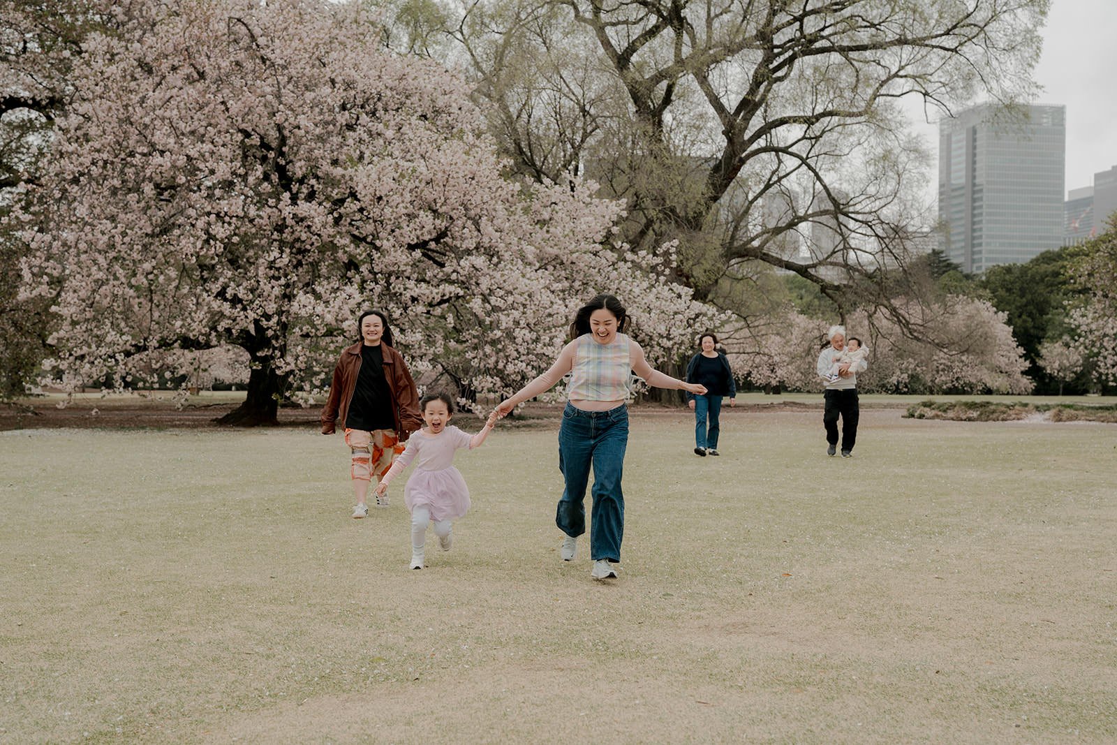 Children running through cherry blossom path at Shinjuku Gyoen