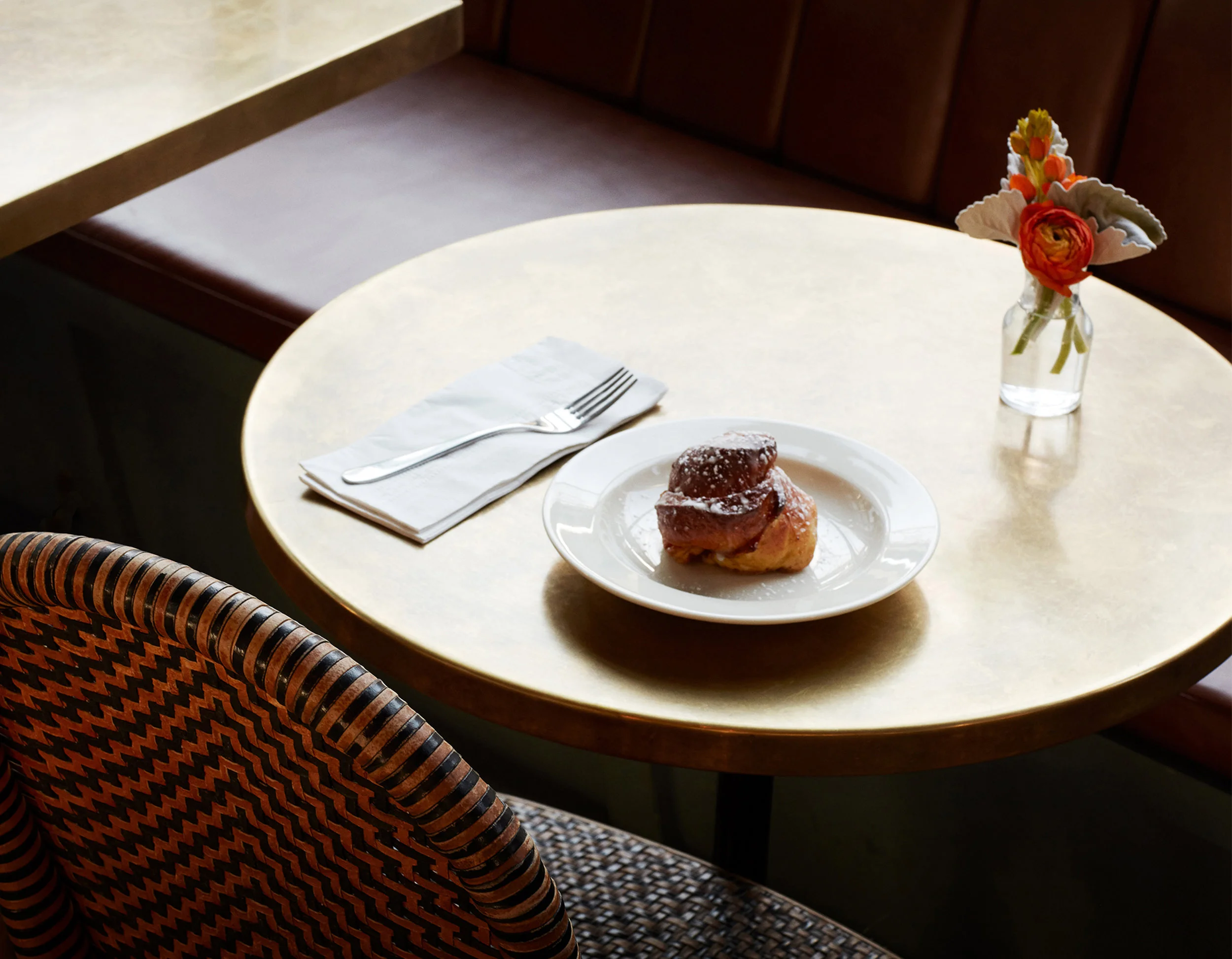 Dolce su piatto bianco su tavolo con forchetta e tovagliolo, vaso di fiori colorati in argento