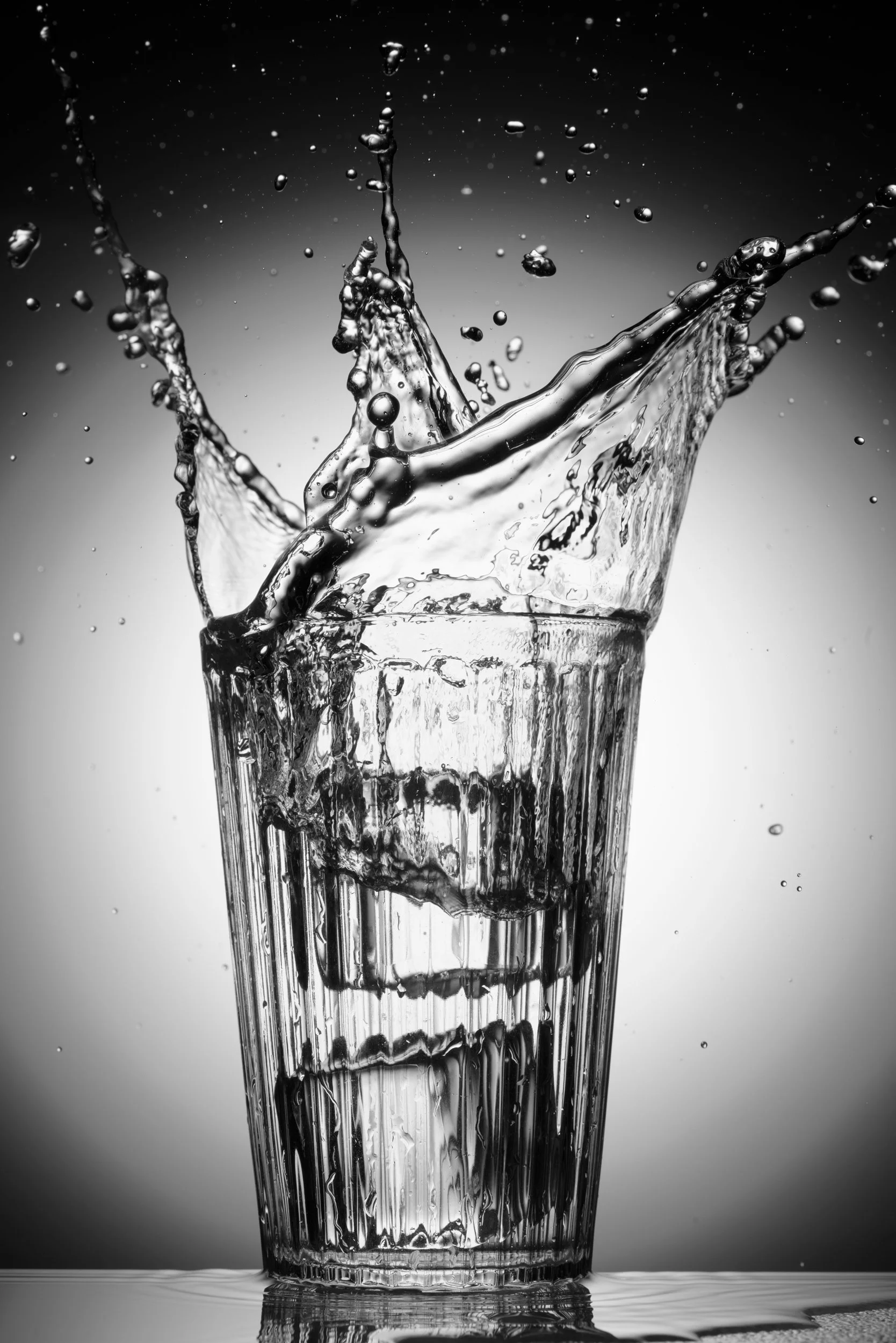 Splash of water captured midair in a clear glass with sharp contrast