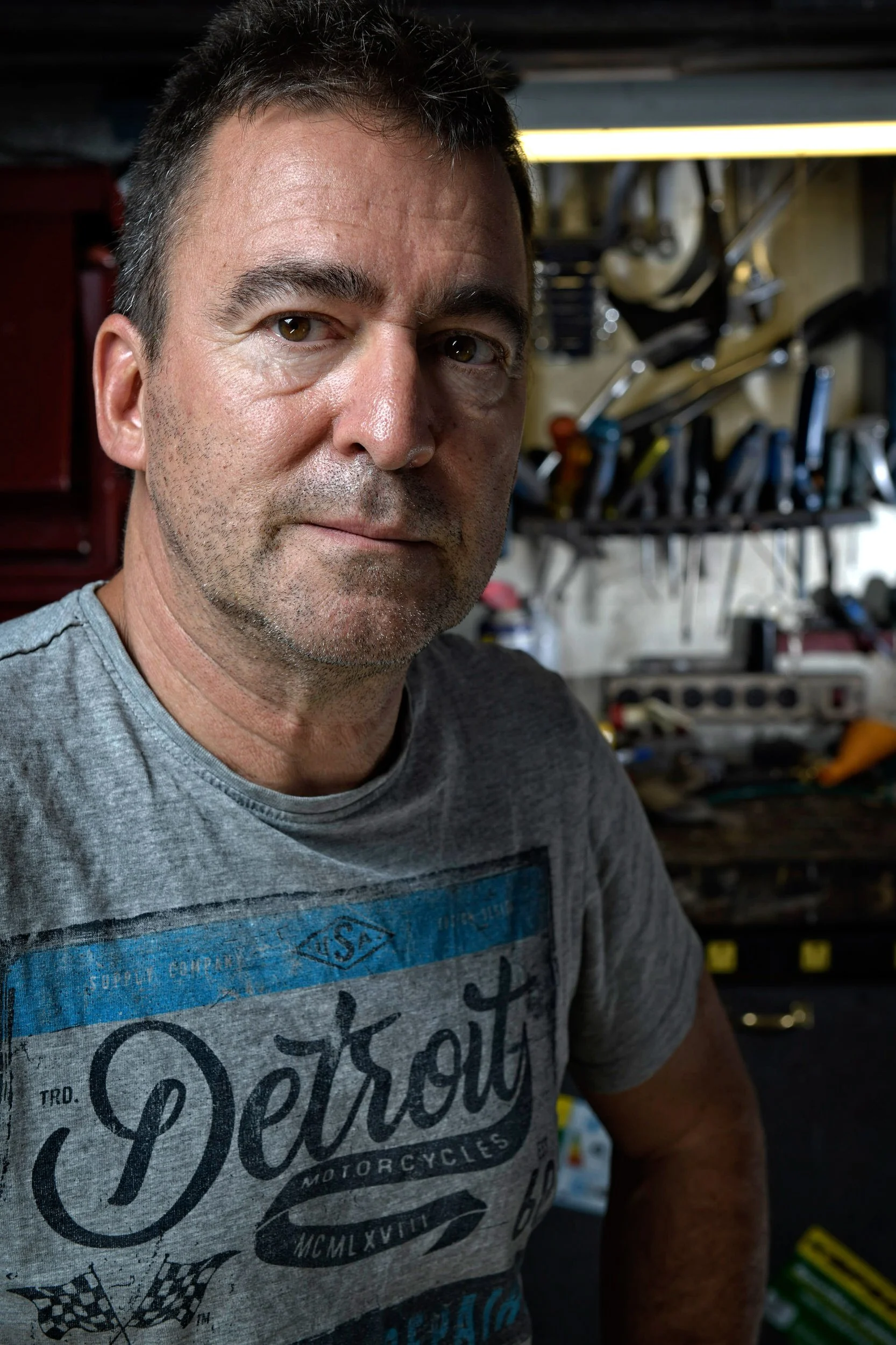 Close-up lifestyle portrait of man in workshop with tools in background