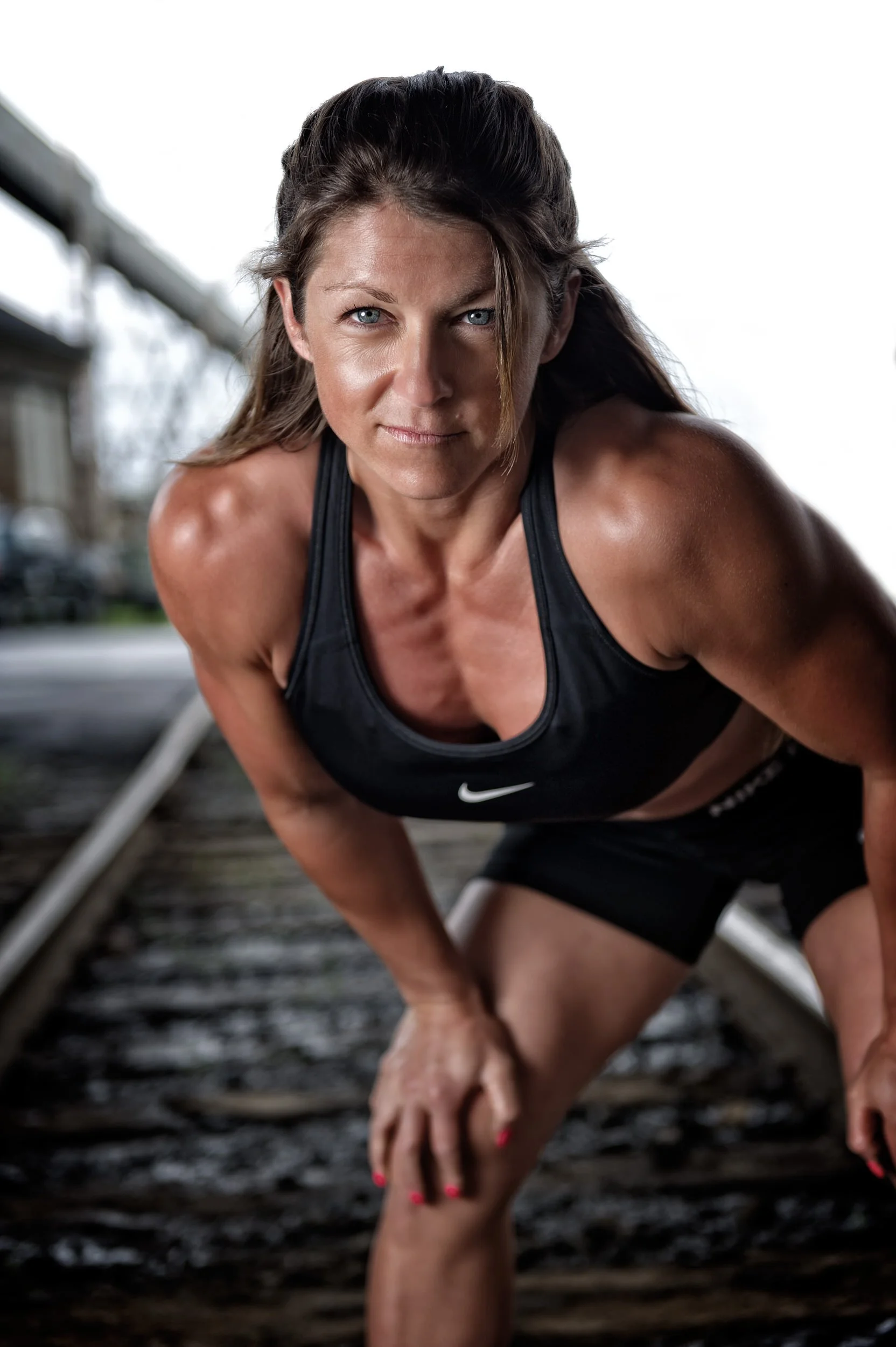 Focused woman bending forward catching her breath on railway tracks