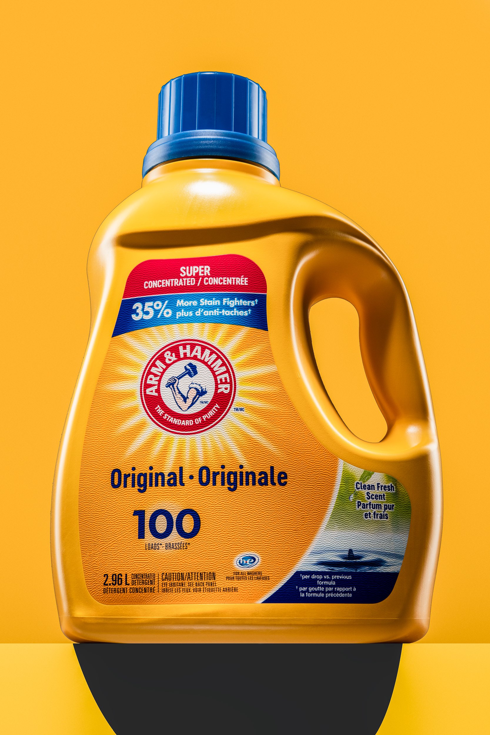 Yellow bottle of Arm and Hammer laundry detergent with blue cap and bold logo, shot by a Montreal product photographer.