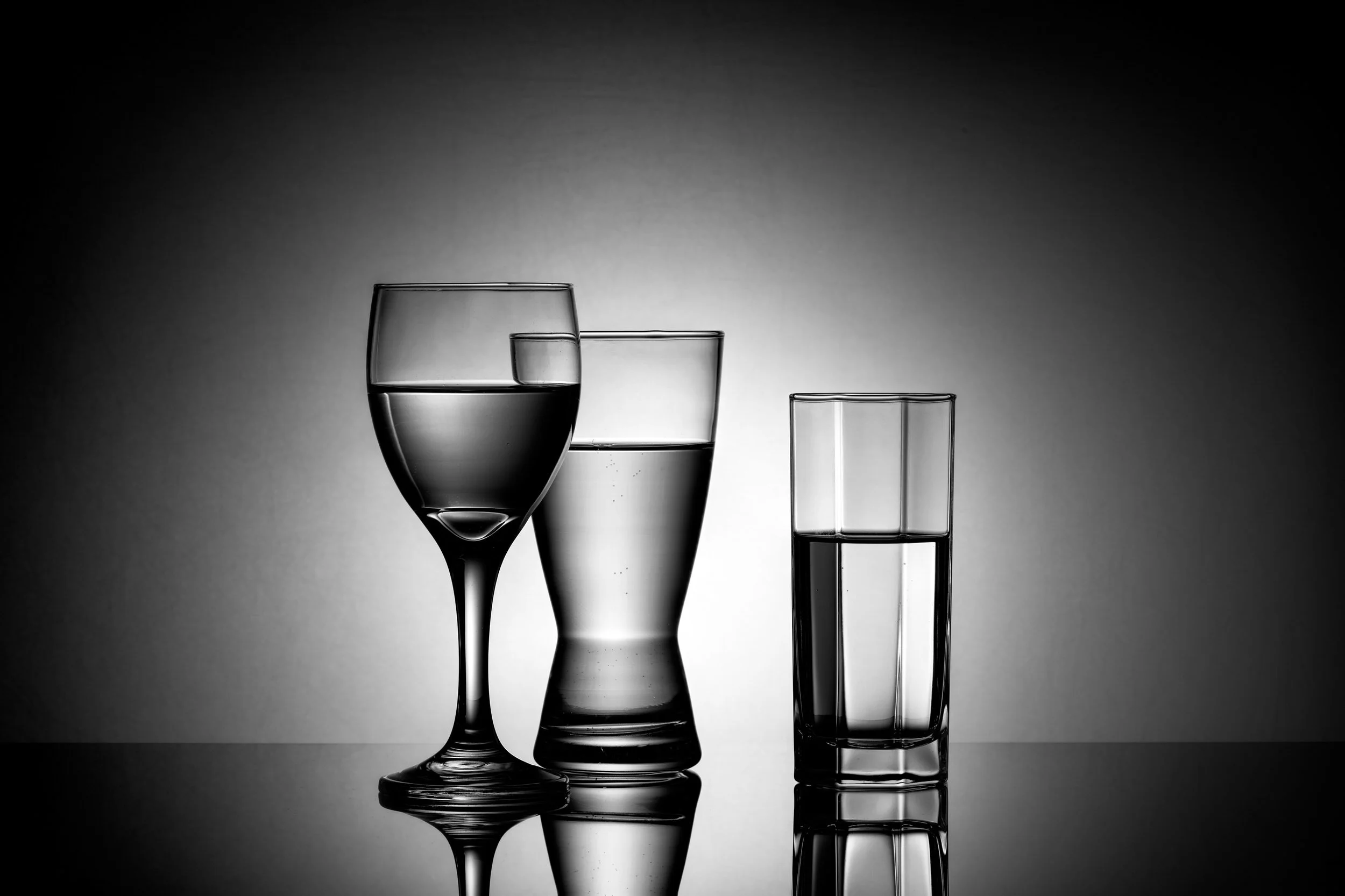 Set of three clear water glasses in different shapes with dramatic backlighting