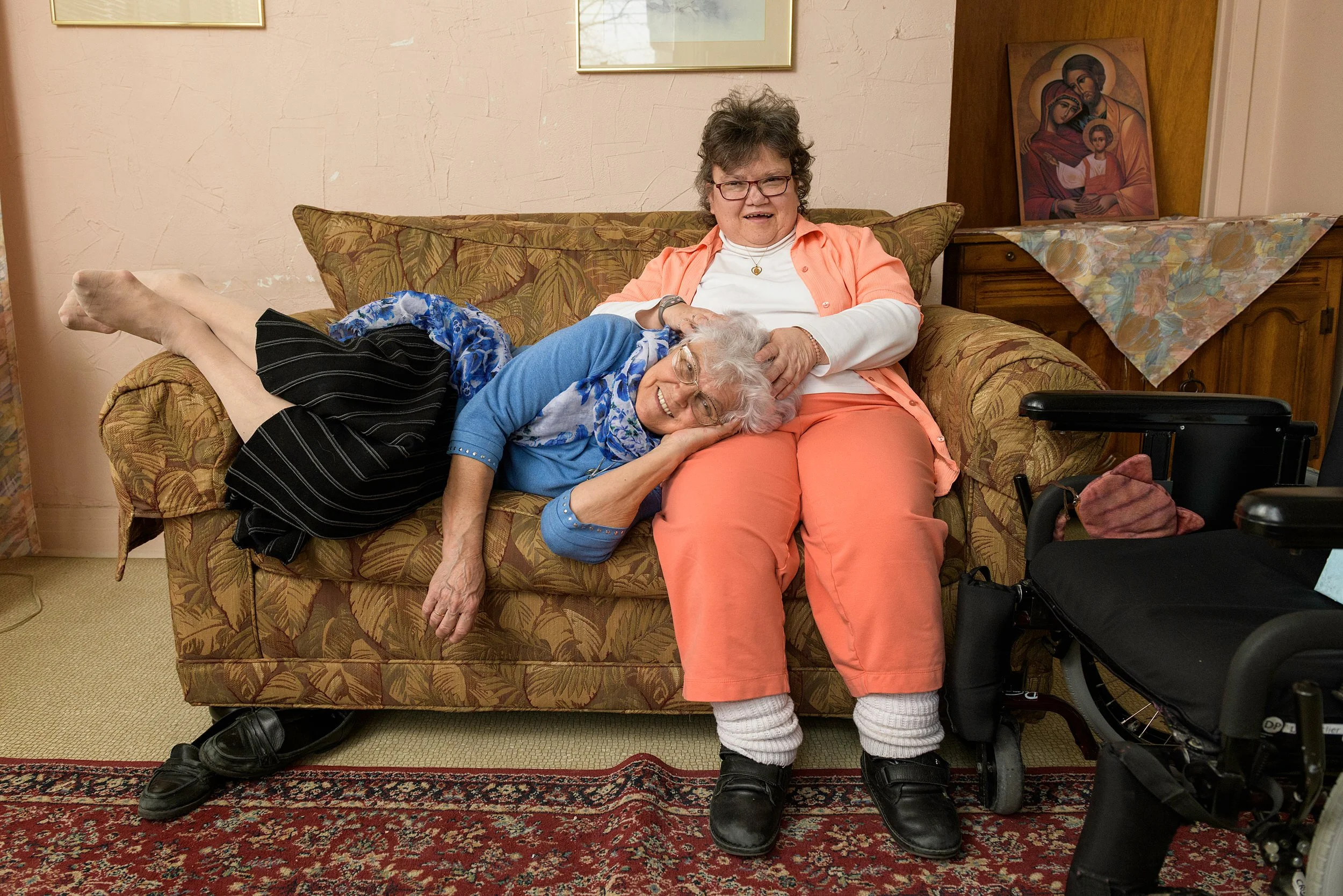 Mother and Daughter relaxing on a couch, smiling and embracing