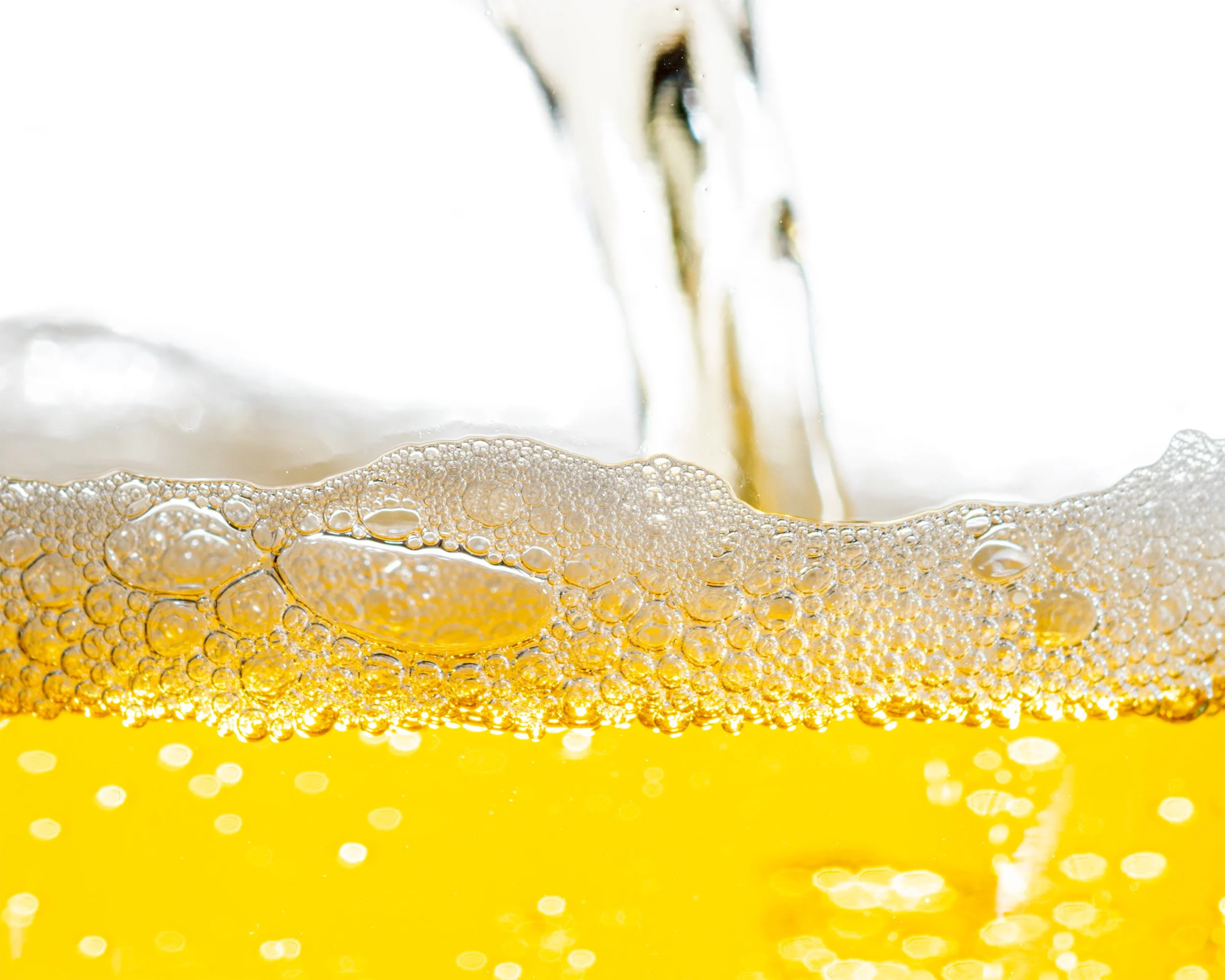 Golden beer pouring with foam and bubbles forming at the surface