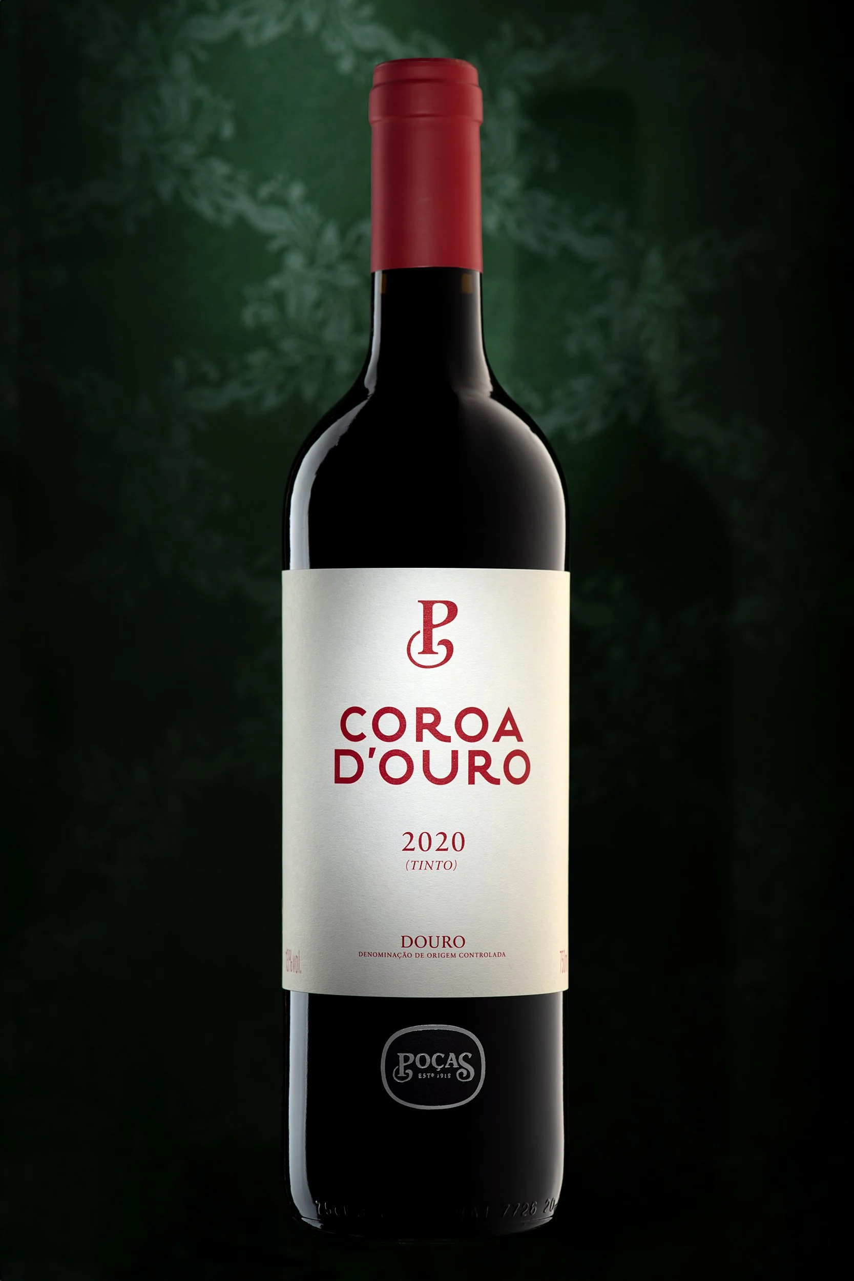 A full bottle of Coroa D’Ouro 2020 red wine shown upright on a deep green background with subtle texture.