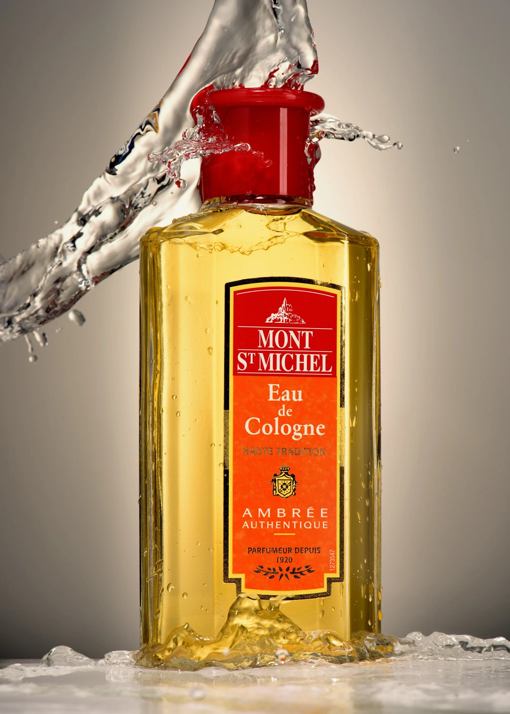 Mont St Michel amber cologne bottle with red cap and water splash in action