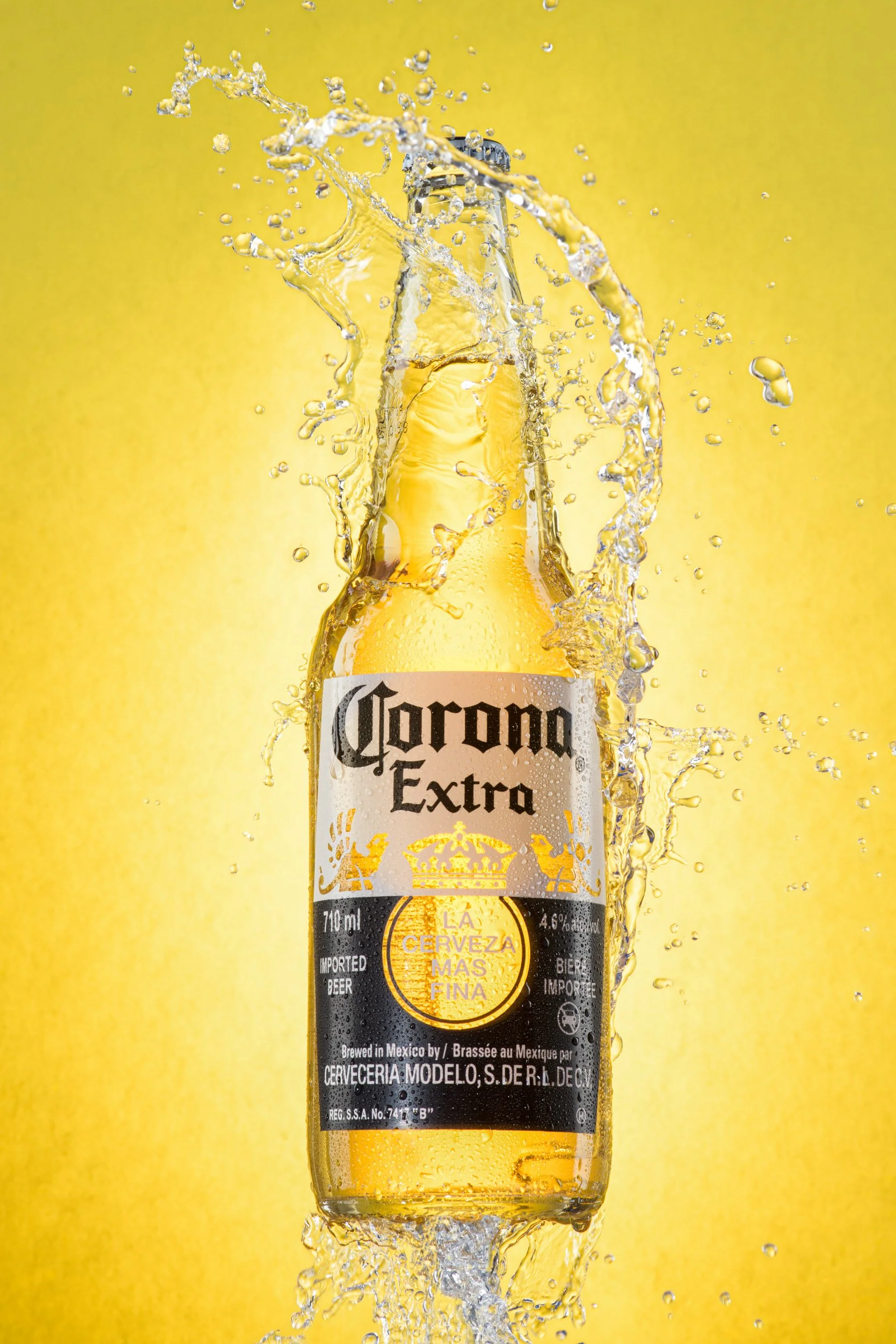 Corona Extra beer bottle with splash effect and bright yellow background