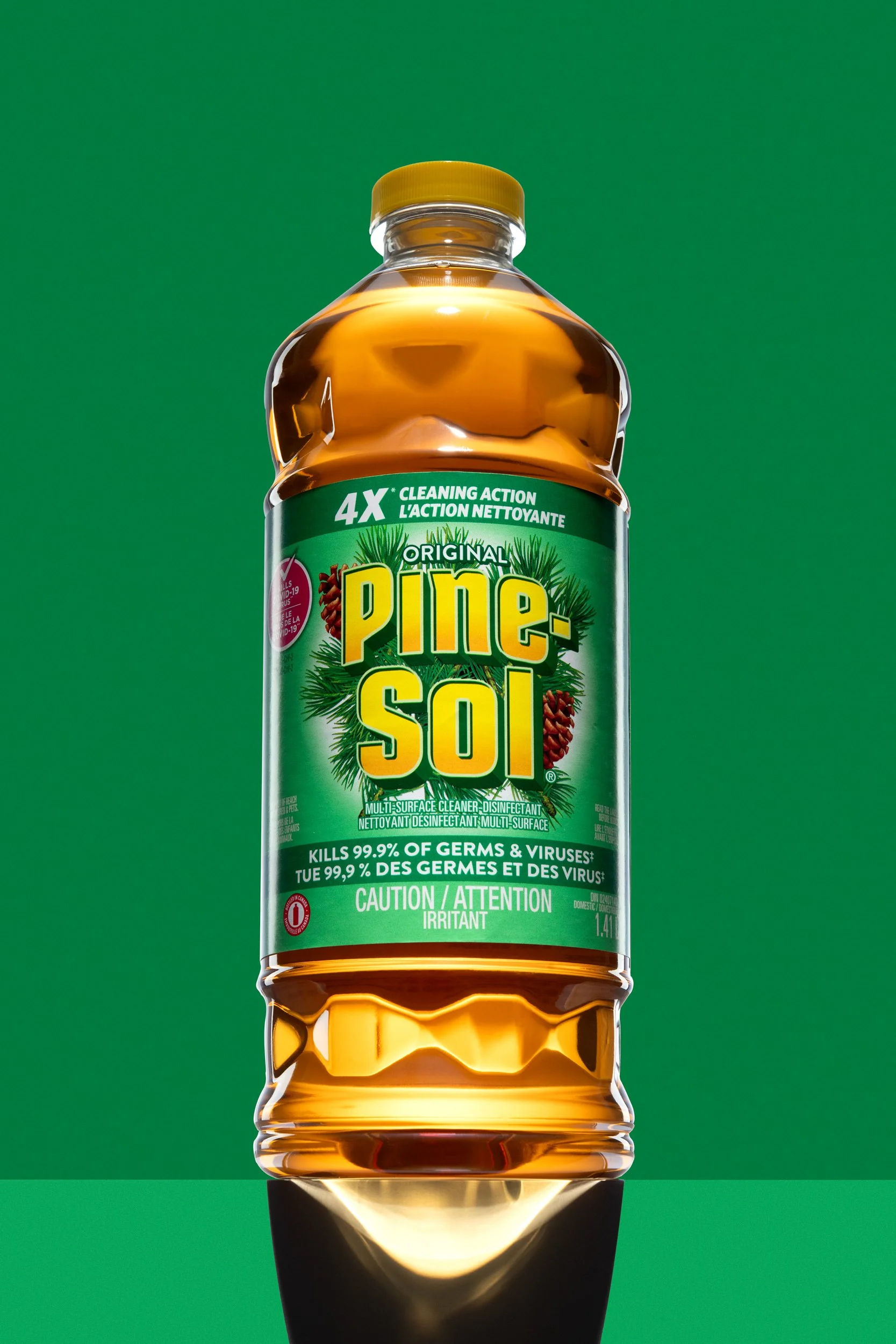 A bottle of Pine Sol cleaner stands on a green background with strong lighting, shot by a Montreal product photographer.
