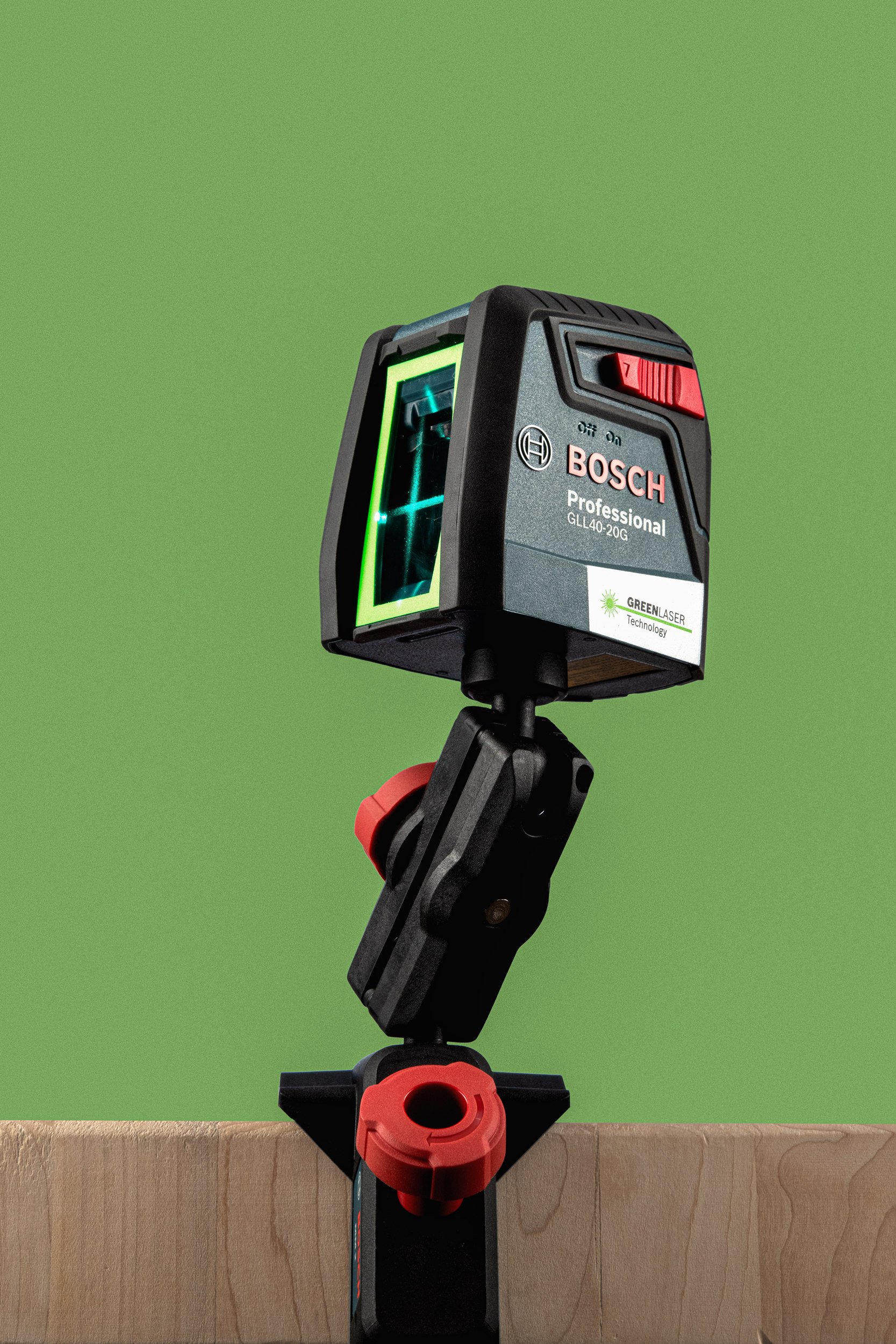Bosch professional laser level tool with green line visible and clamp attachment