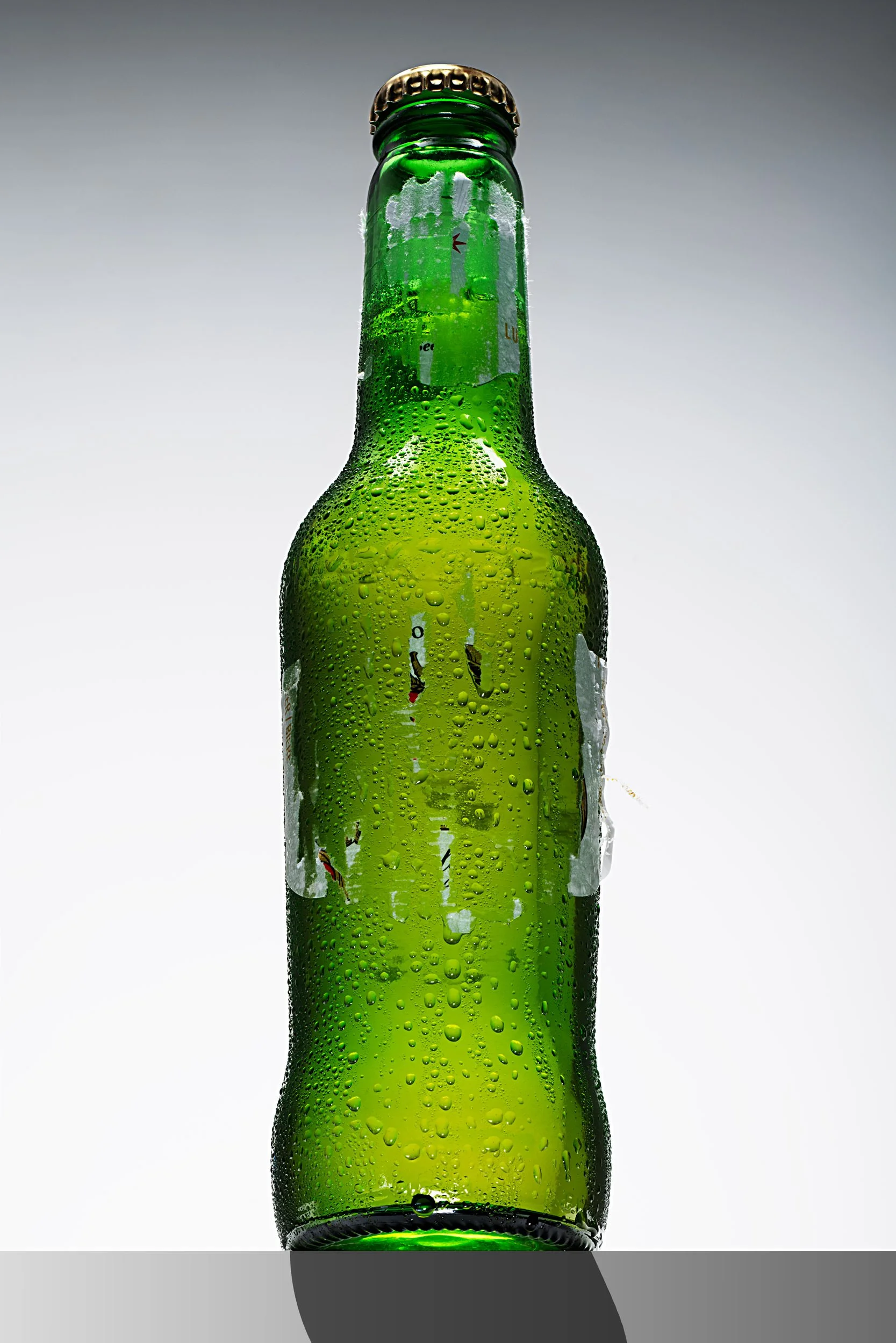 Front view of a green beer bottle with condensation on white background