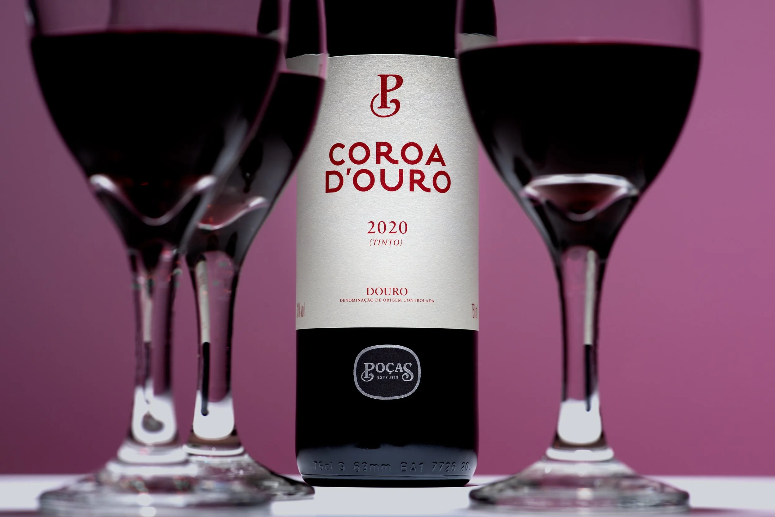 Tight framing of the Coroa D’Ouro red wine label surrounded by out-of-focus wine glasses in the foreground.
