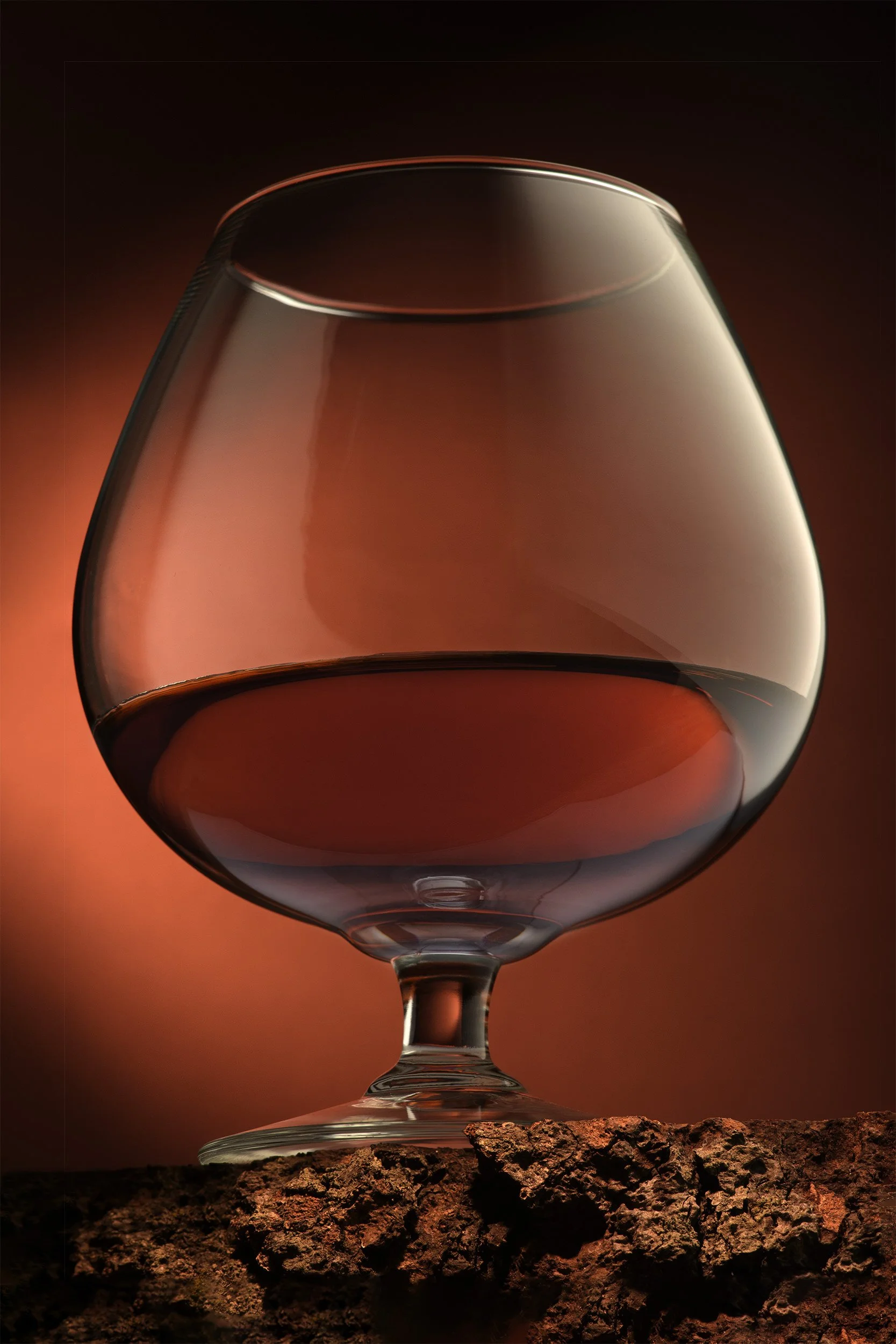 Snifter glass of brandy with warm amber light and cork texture