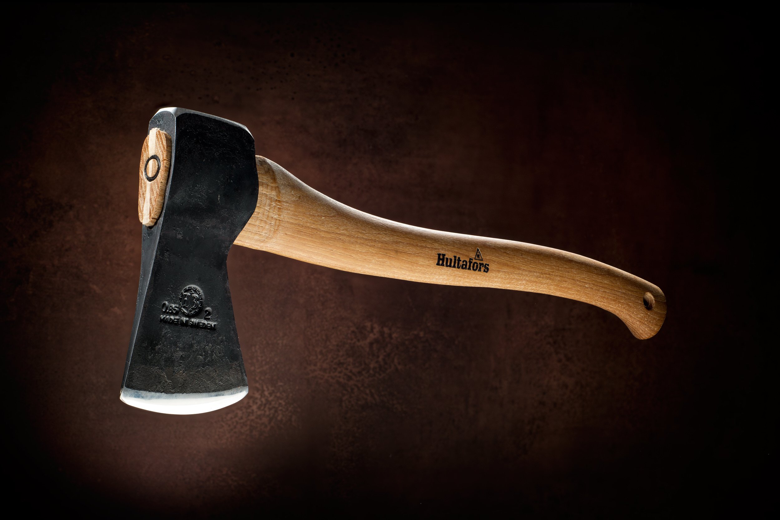 Classic wood handle Hultafors axe floating against textured brown backdrop