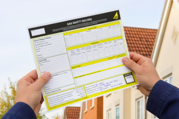 Gas Safe engineer holding a completed Landlord Gas Safety Certificates (CP12) in front of a residential property in Wokingham.