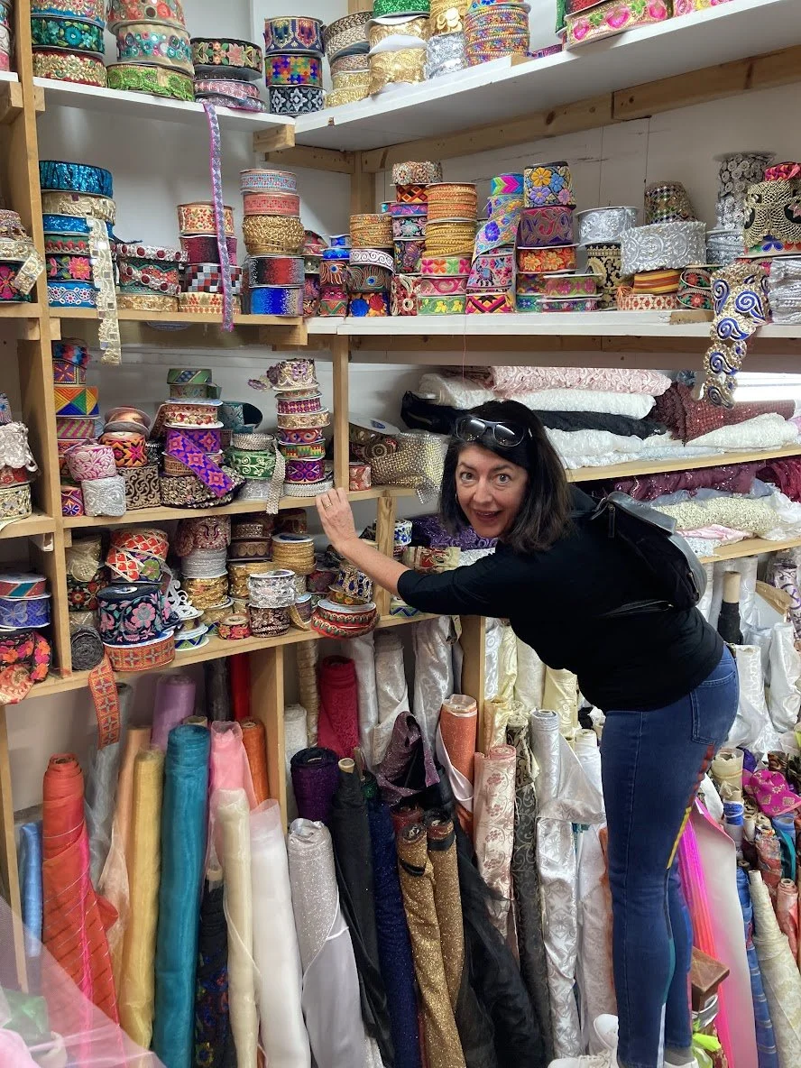 Image of designer Pam Daniels in front of a wide range of colorful trims and ribbons in a fabric store