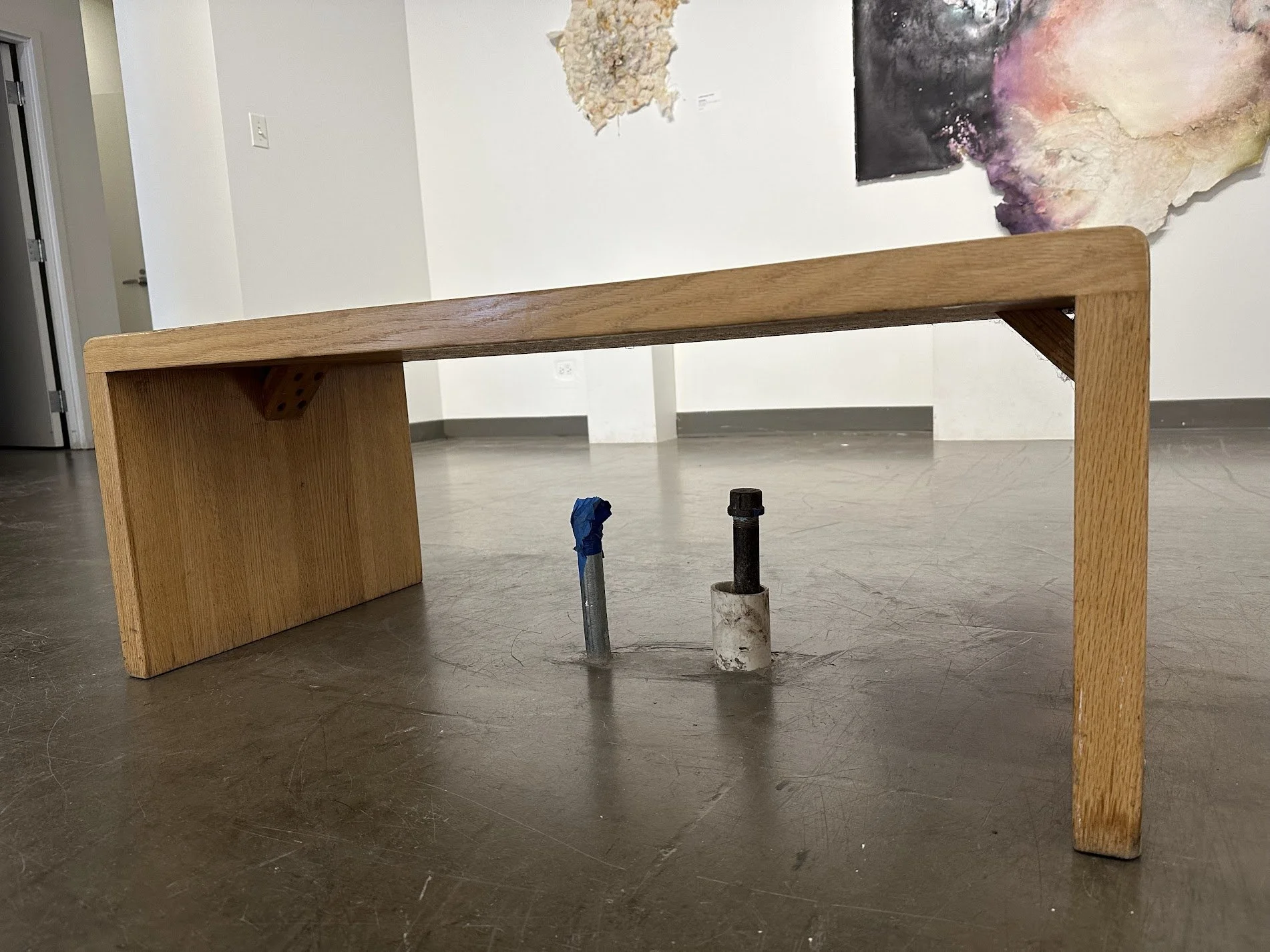 Image of a wooden bench in an art gallery with exposed pipes below it